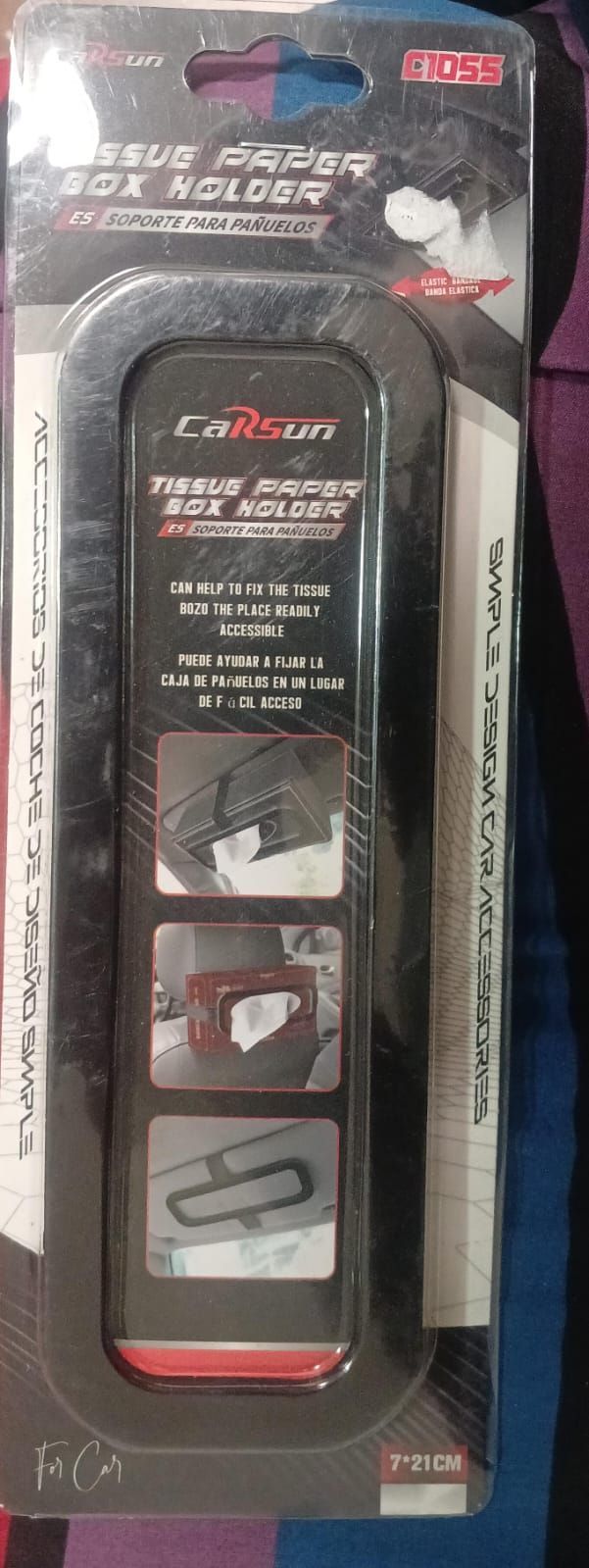 Caja de pañuelos gris en el respaldo del asiento de un automóvil, una mano sacando un pañuelo, vista de la ciudad de fondo.