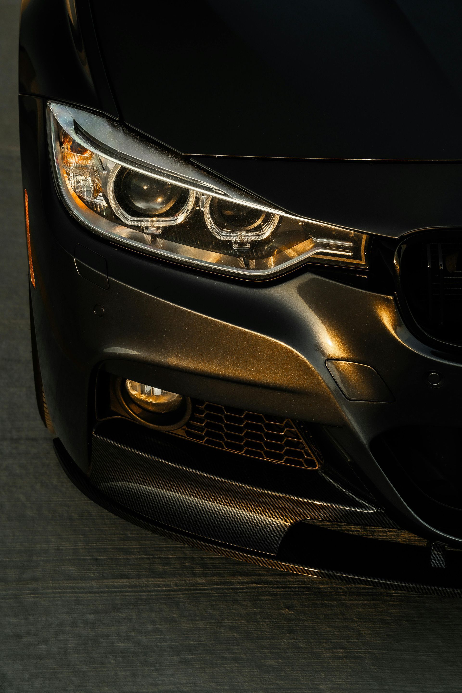 Frontal de coche BMW de color negro con faros iluminados y luz antiniebla.