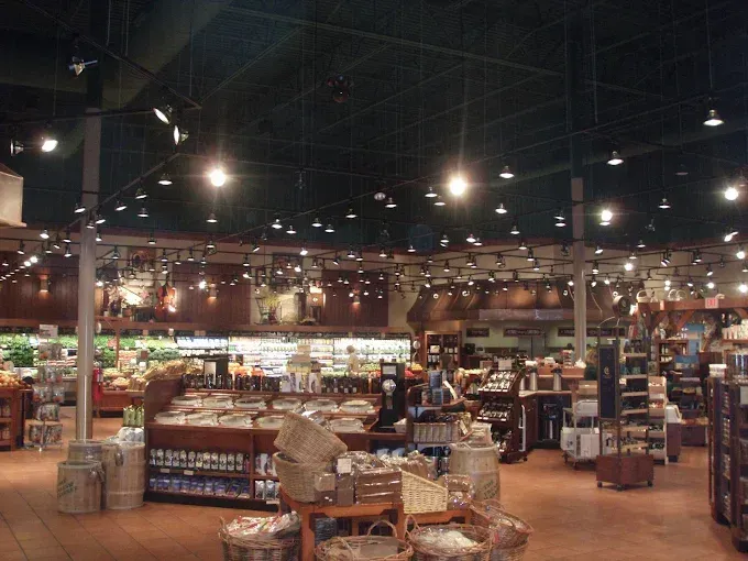 Interior of a well-lit grocery store with various food displays, wooden shelving, and overhead lighting.
