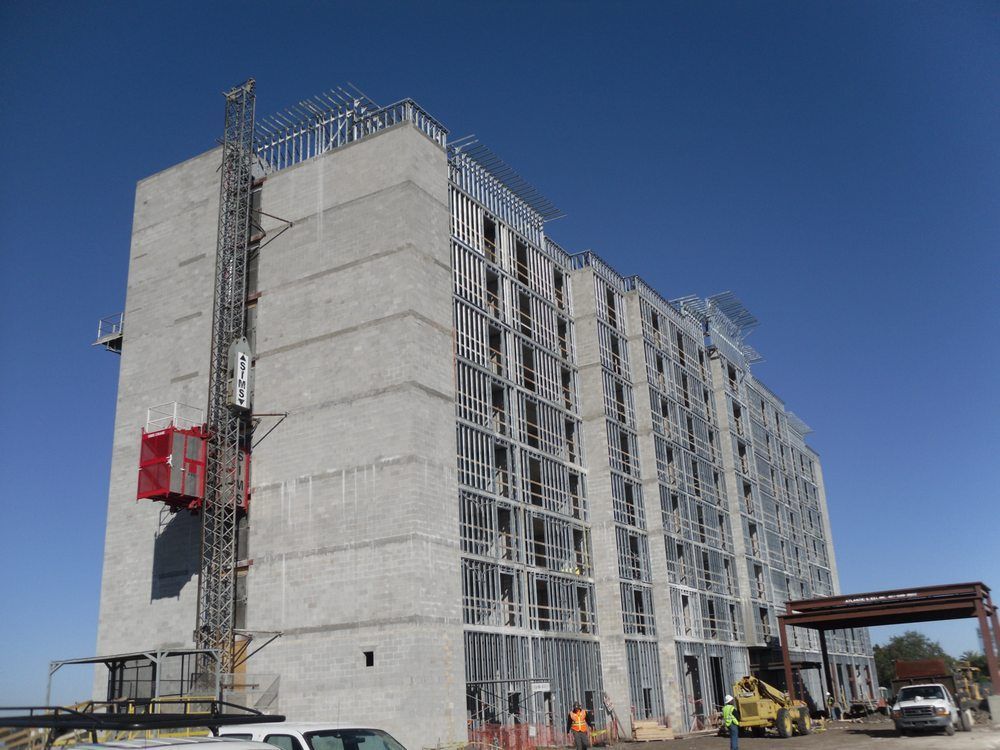 Multi-story building under construction with a construction lift and workers.