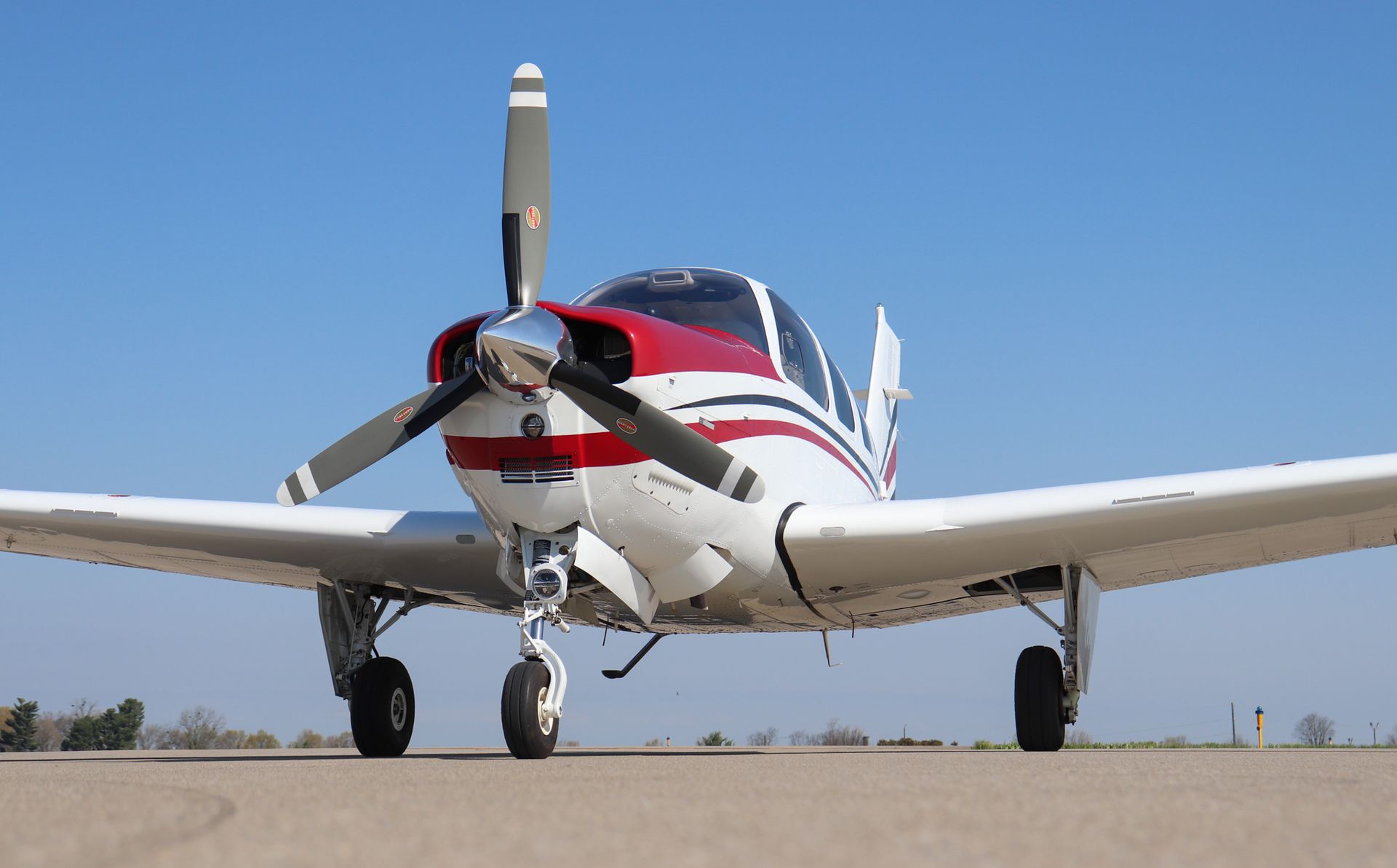 A small propeller plane is flying over an airport runway.