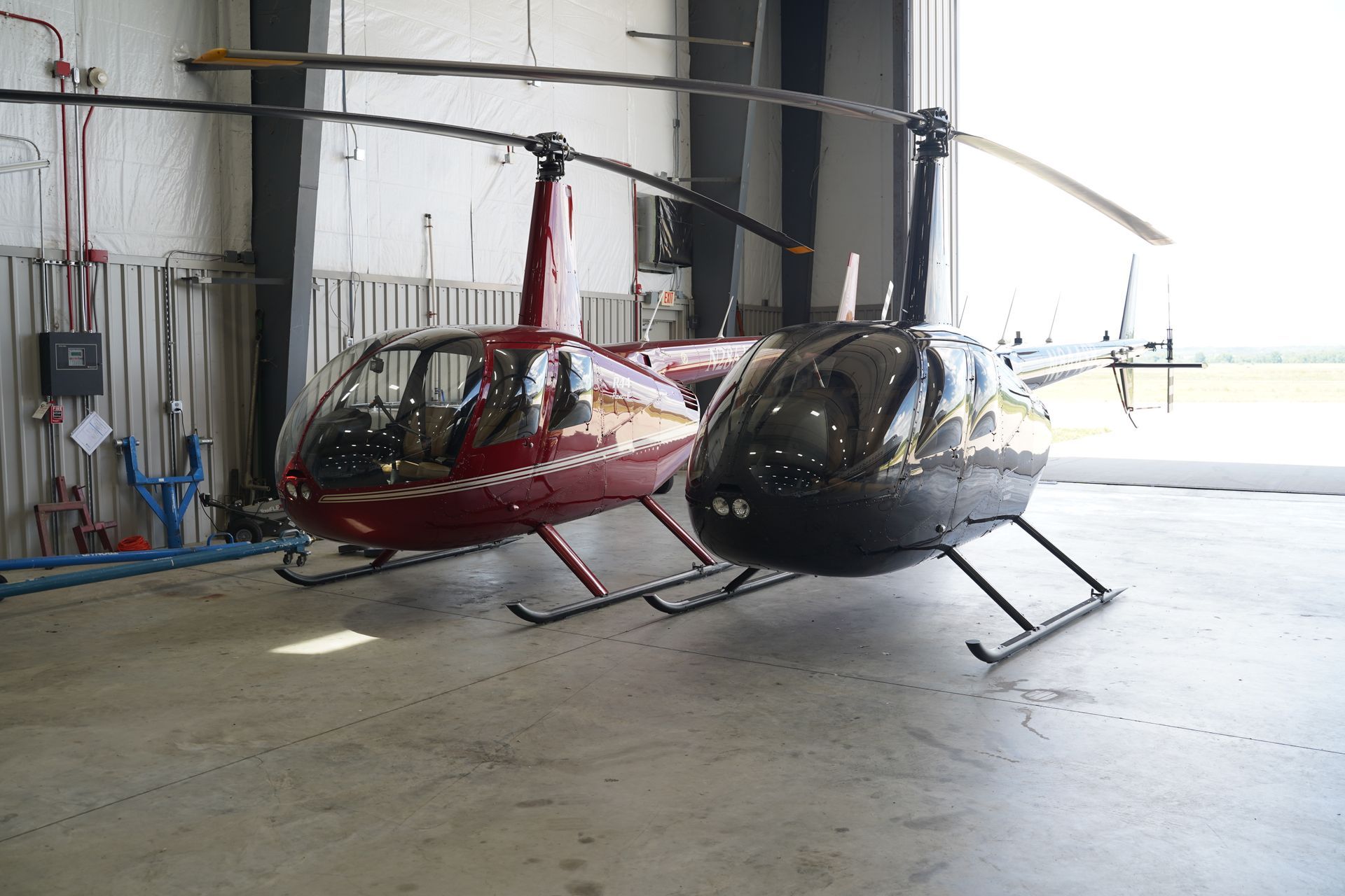 A man is working on a red helicopter in a hangar.