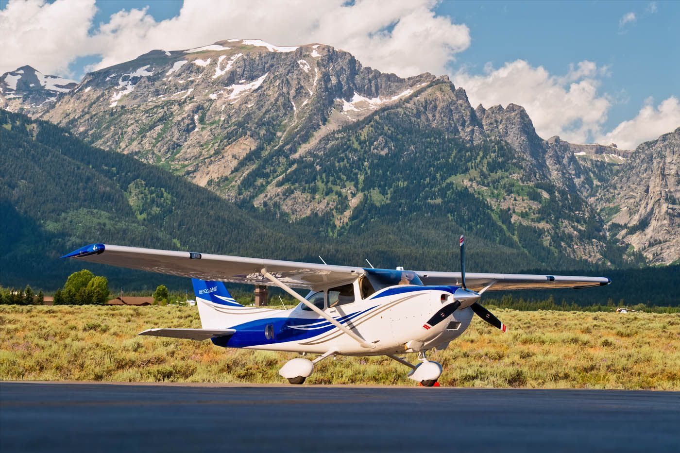 A small plane is sitting on a runway with mountains in the background.