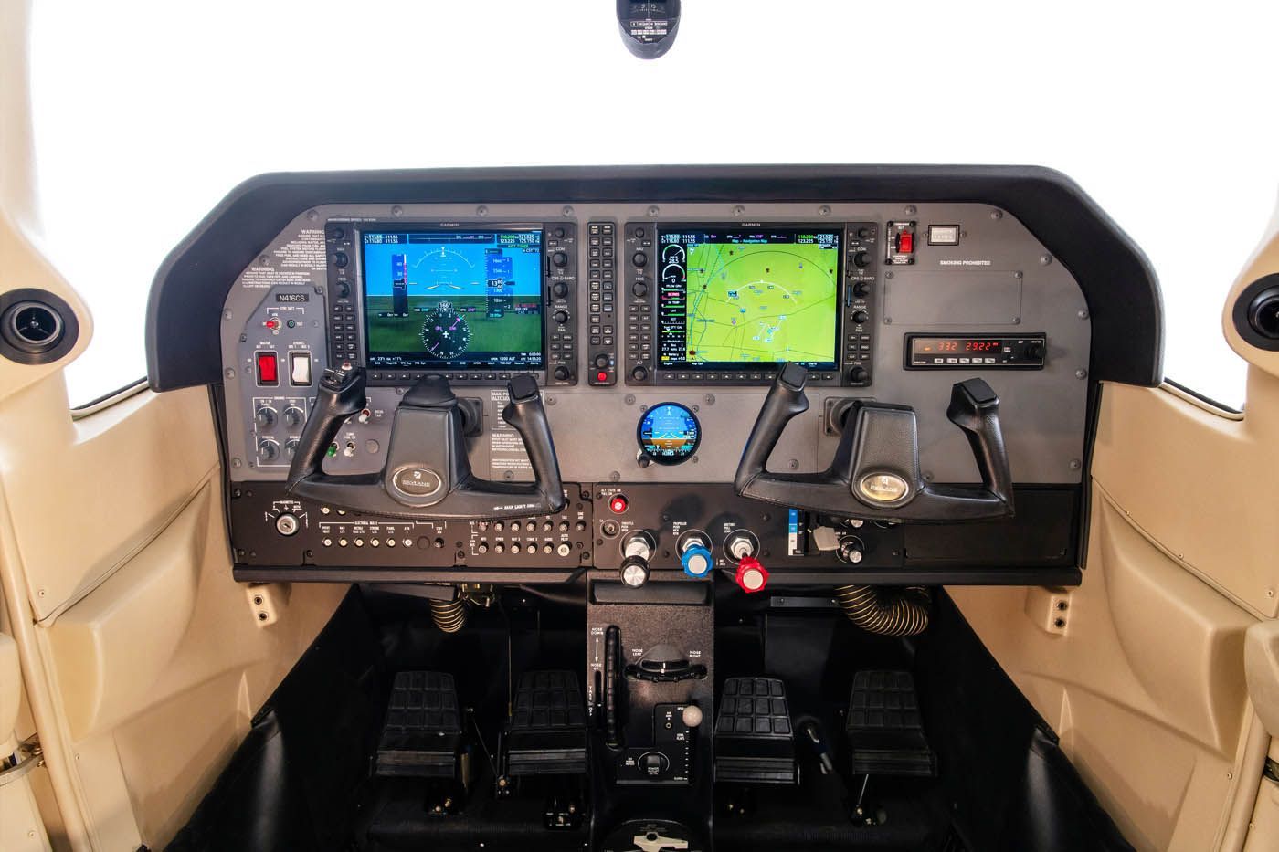 A cockpit of an airplane with two monitors and a gps