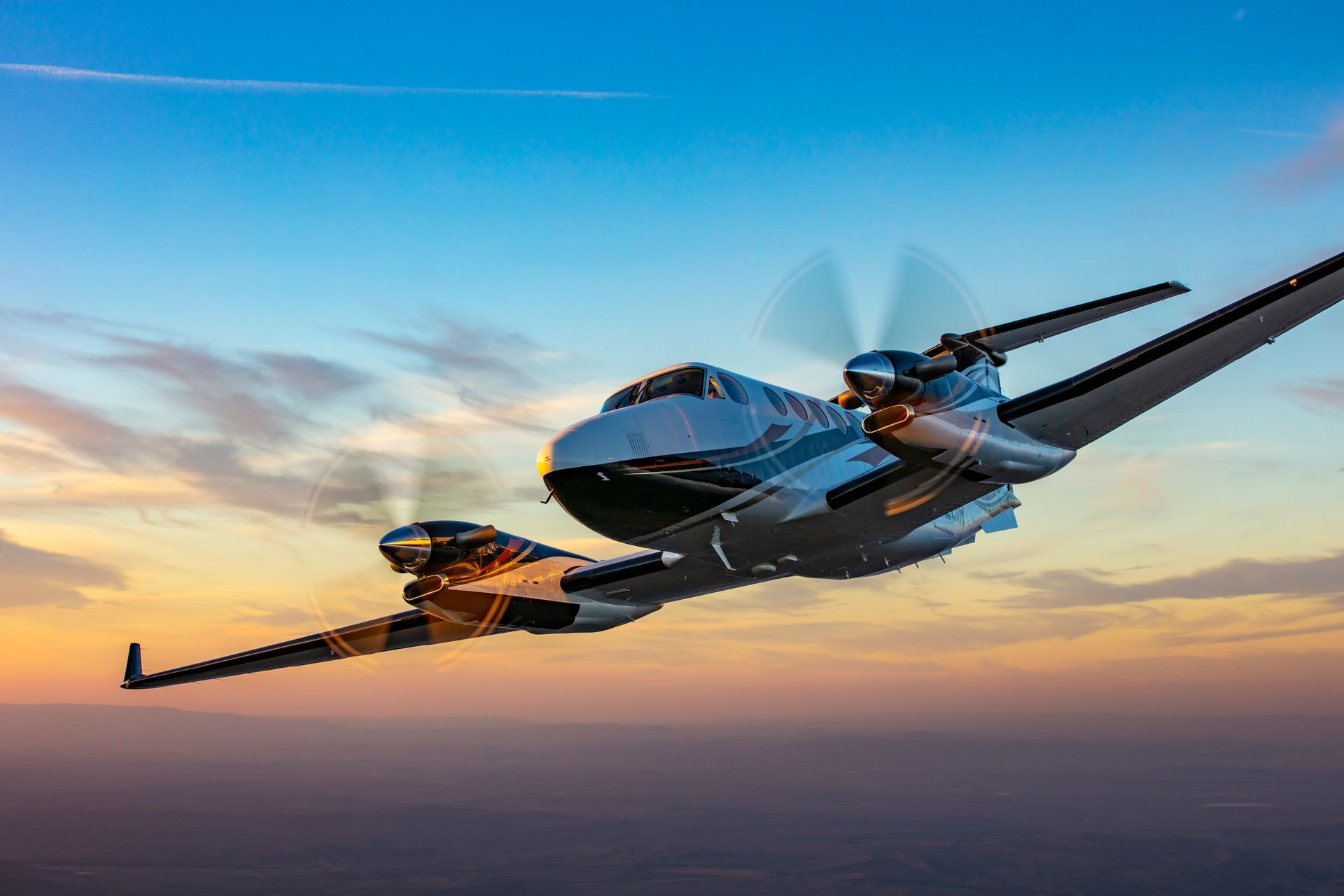 A small propeller plane is flying over an airport runway.