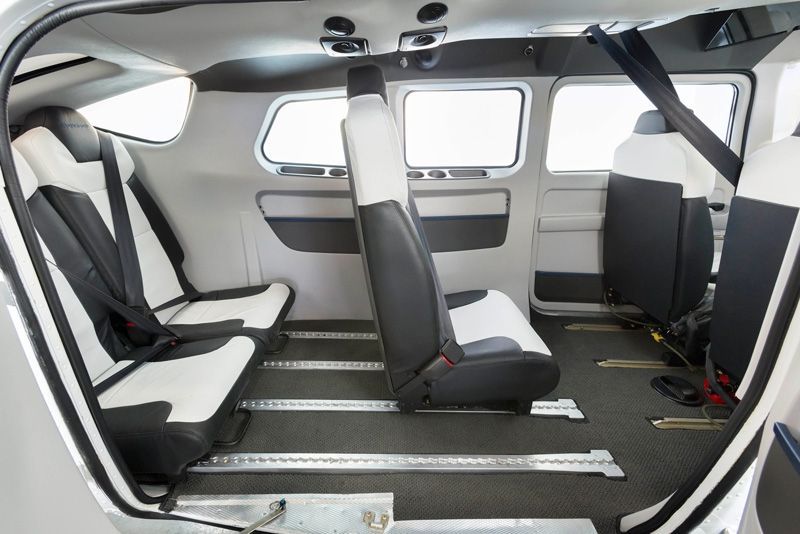 The inside of a small plane with black and white seats.