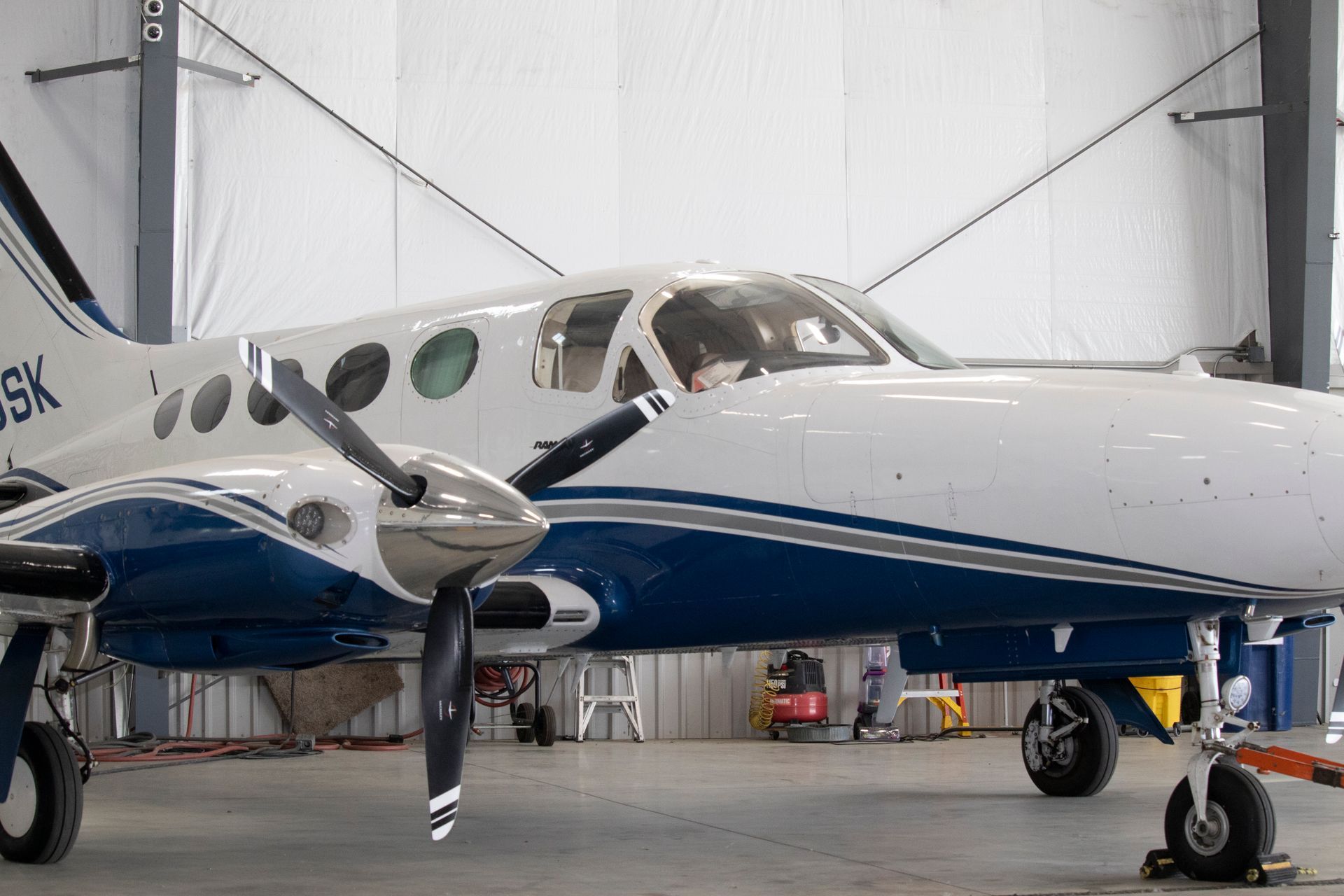 A blue and white airplane with the letters sk on the side is parked in a hangar