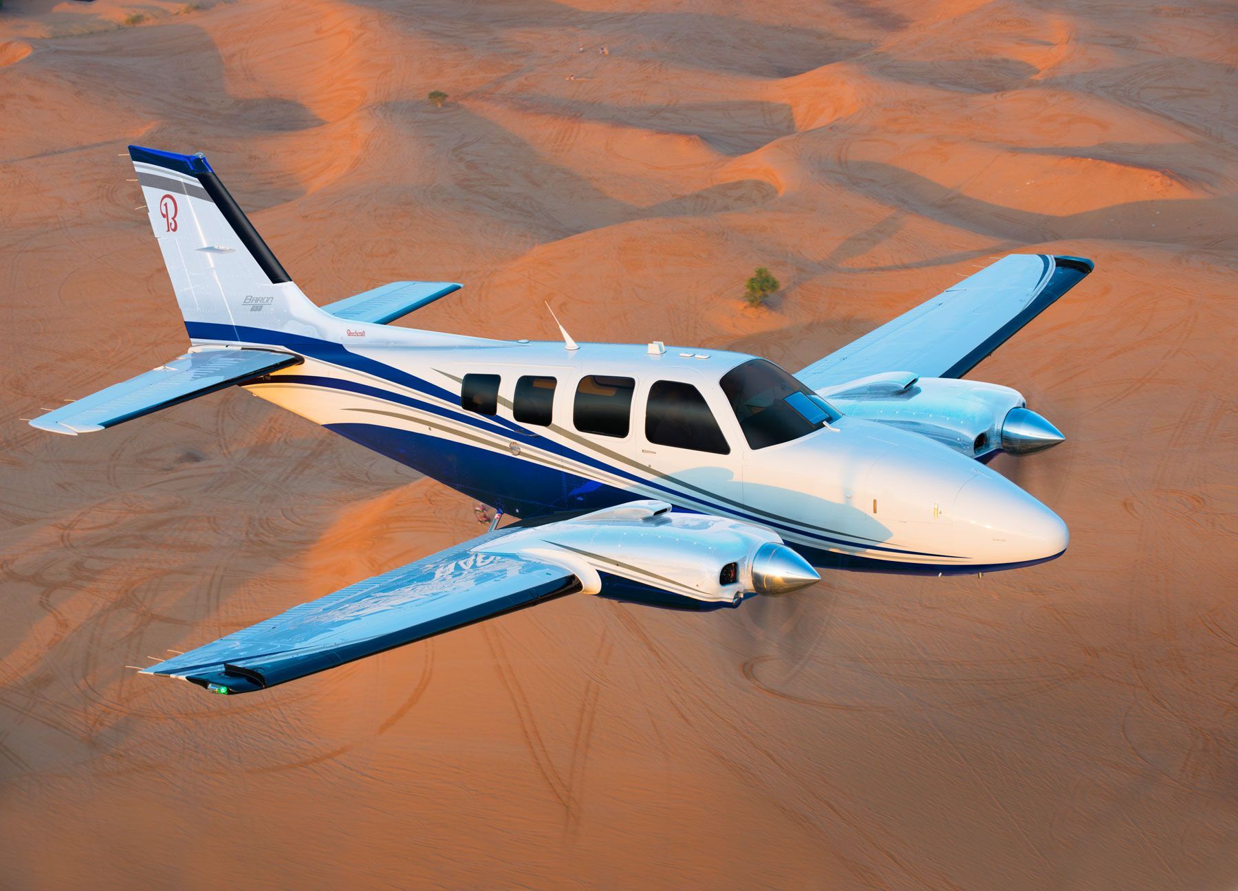 A small propeller plane is flying over an airport runway.