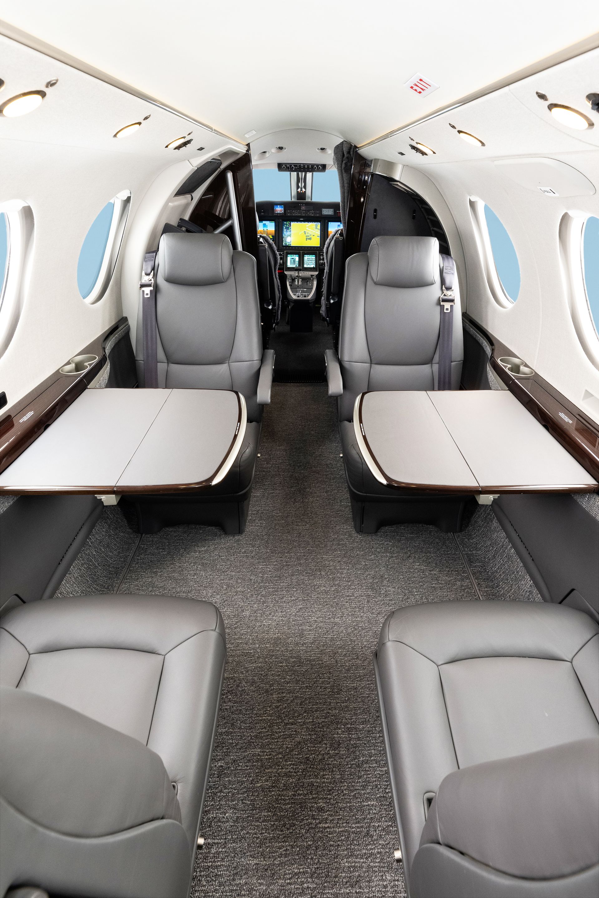 The inside of a private jet with brown leather seats and a cockpit.