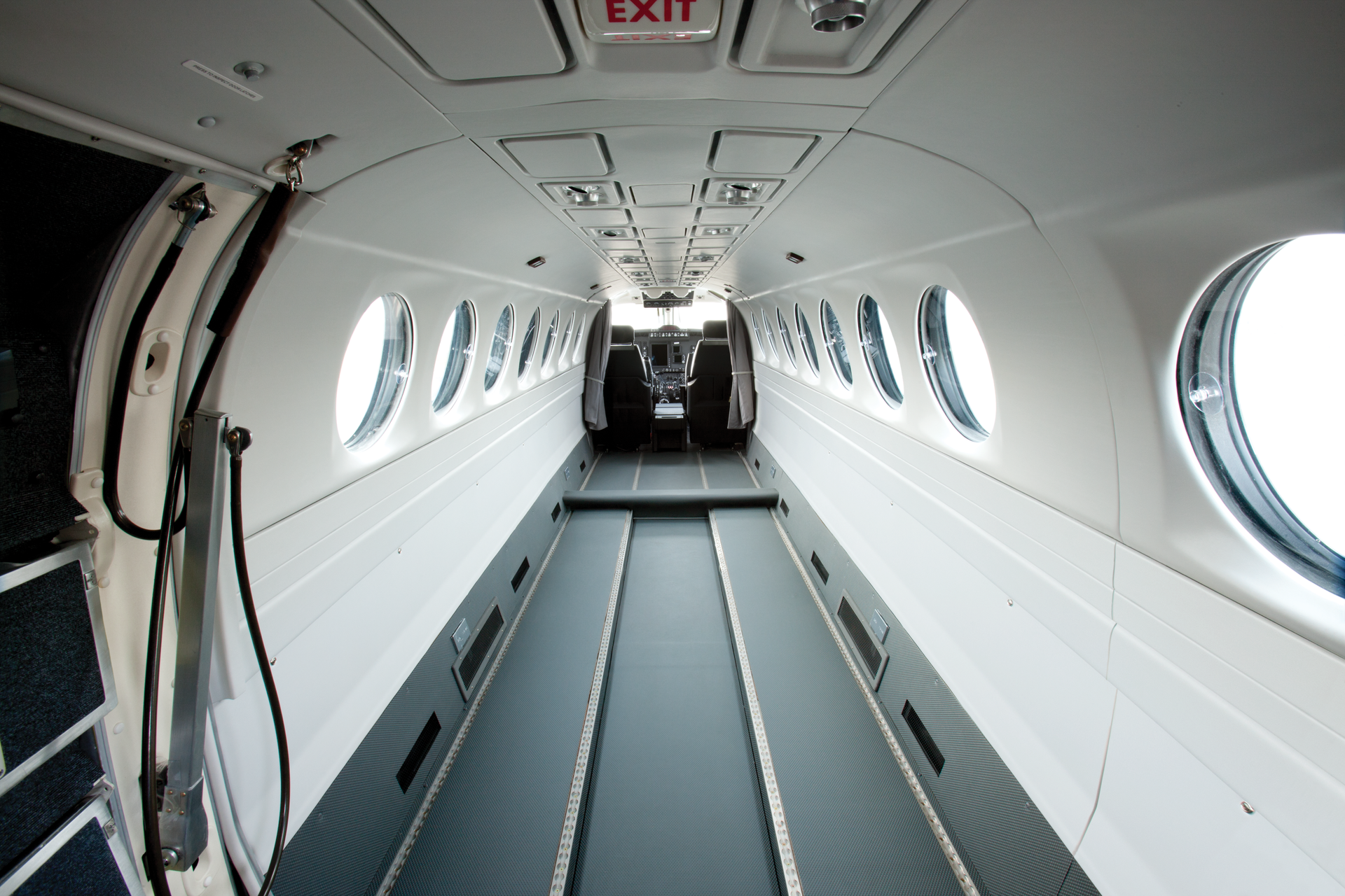 The inside of a private jet with brown leather seats and a cockpit.