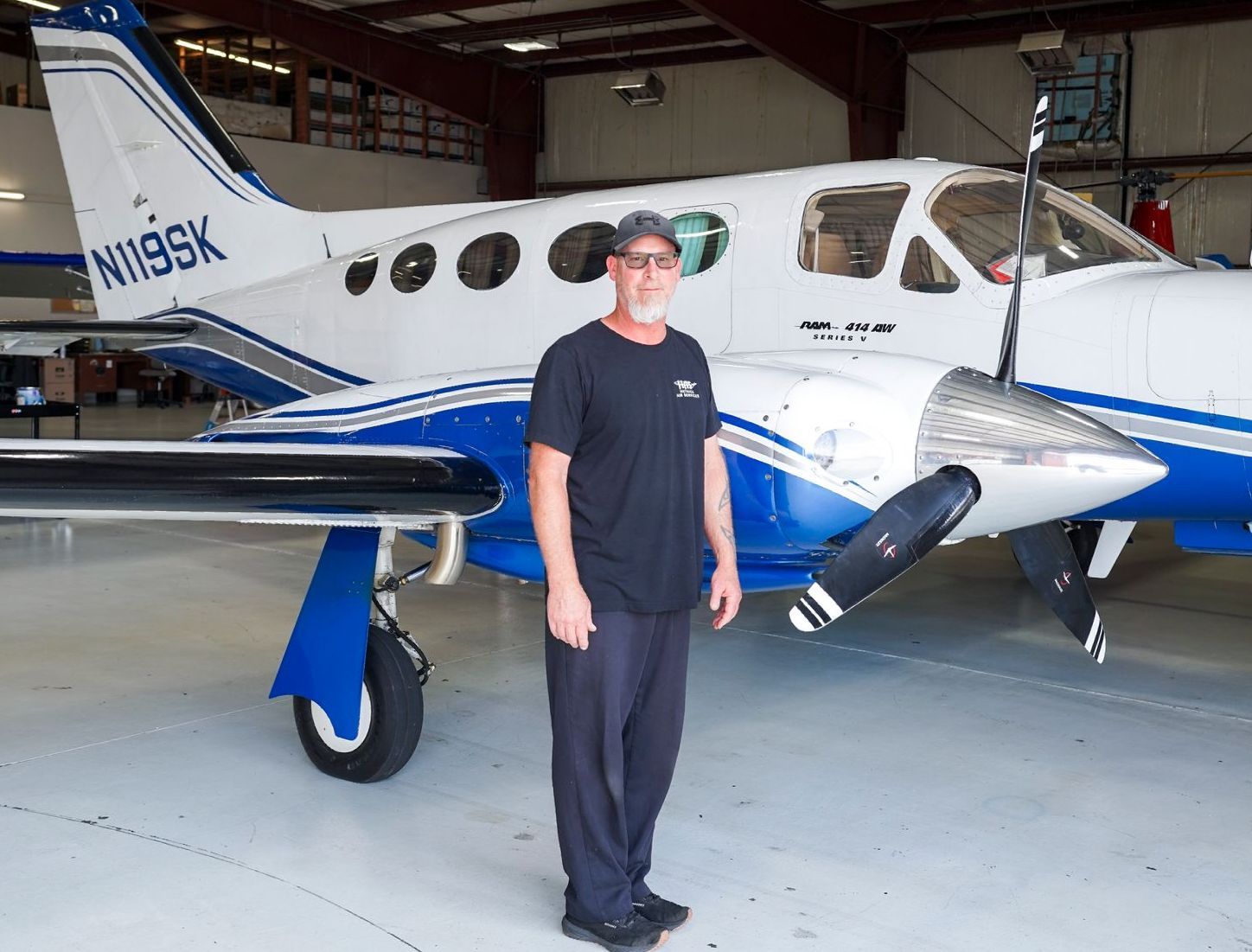 A man stands in front of a small plane with n119sx on the tail