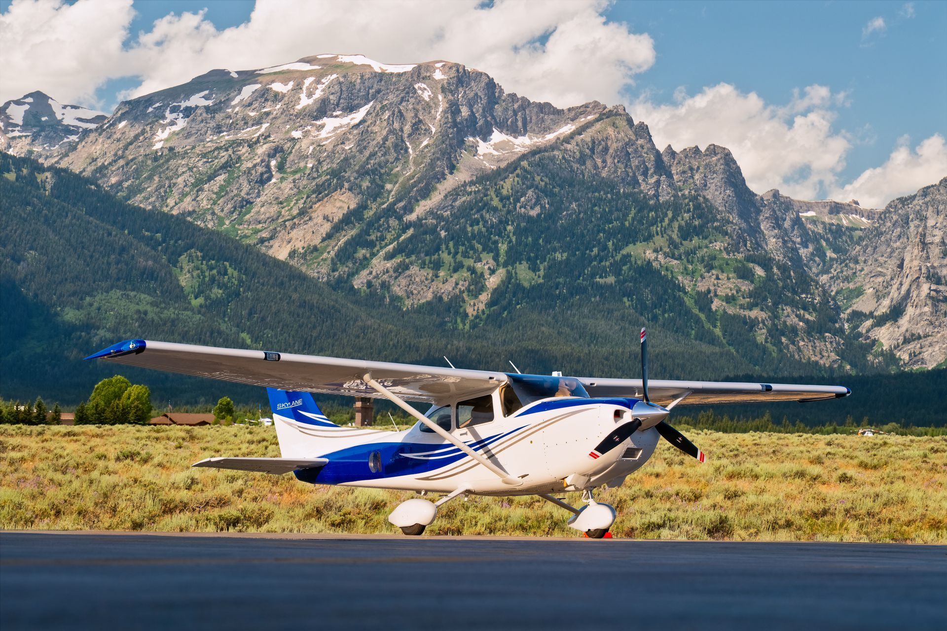 A small plane is sitting on a runway with mountains in the background