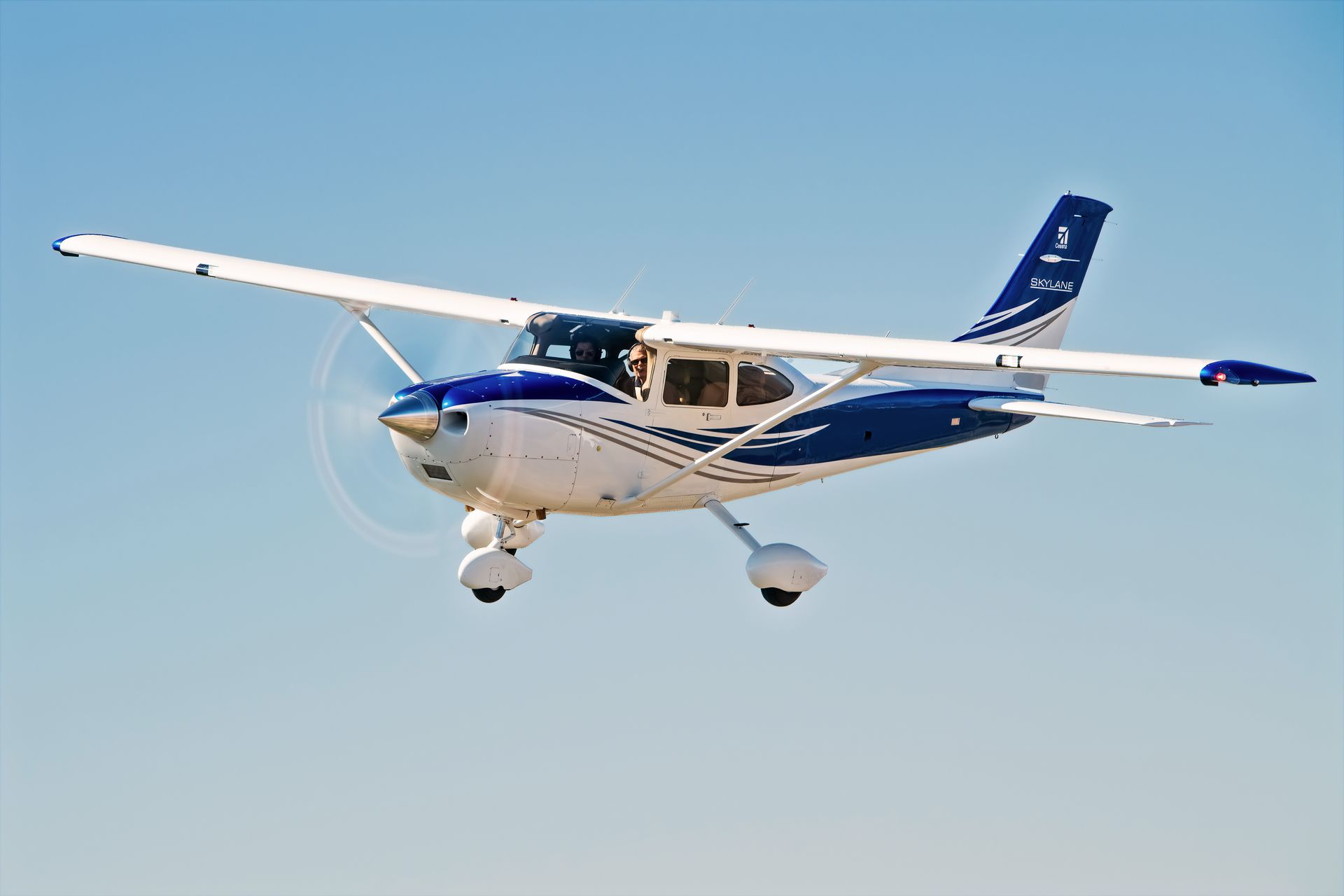 A small blue and white plane is flying in the sky.