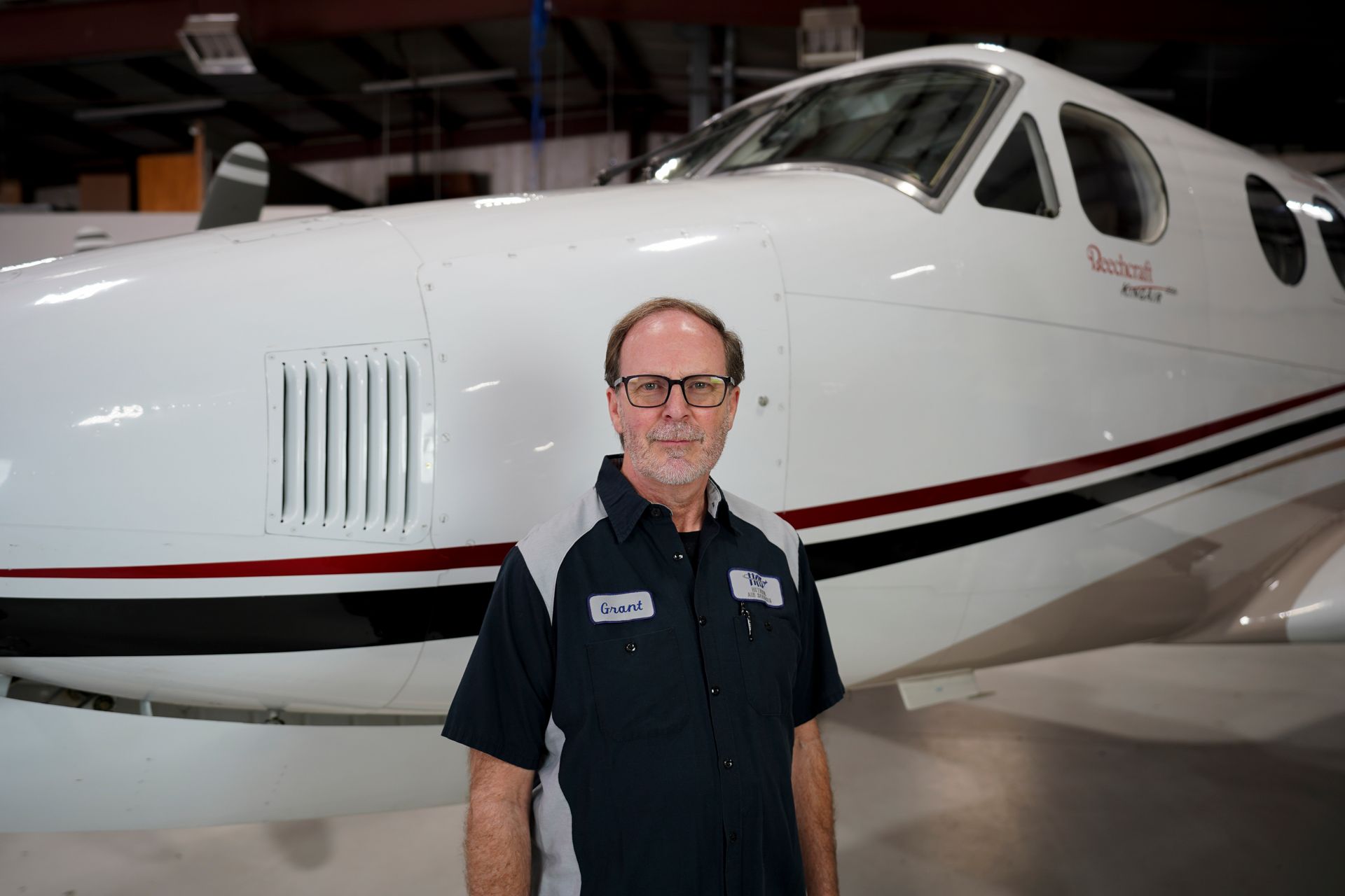 A man is standing in front of a small airplane in a hangar.