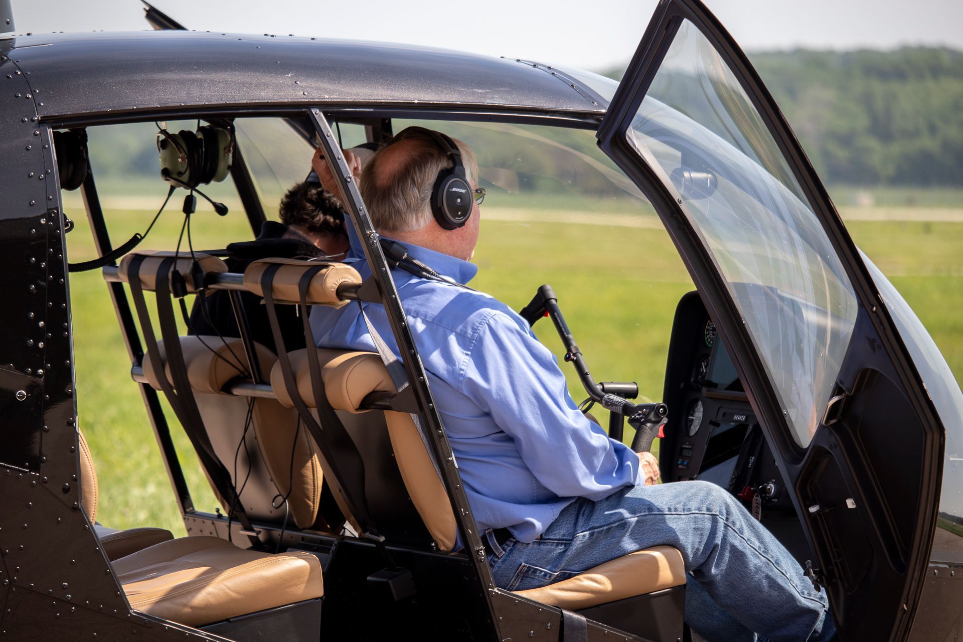 A man is sitting in a small helicopter with the door open.