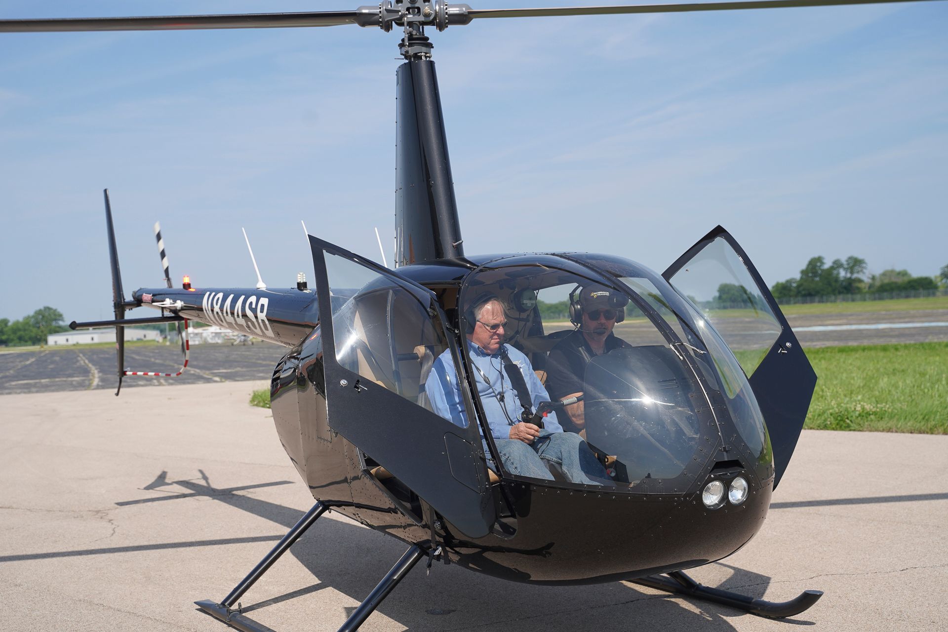 A man is sitting in a small helicopter with the door open.