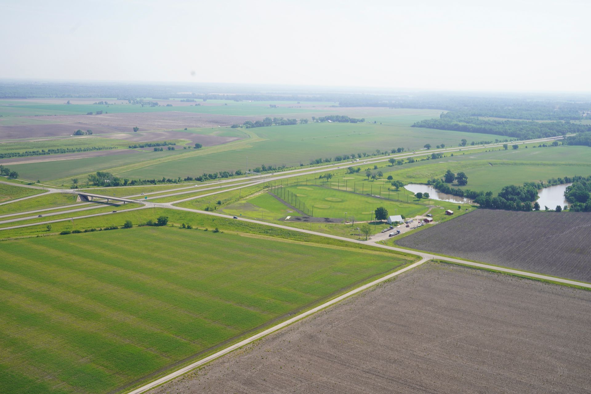 An aerial view of a lush green field with a river in the background.