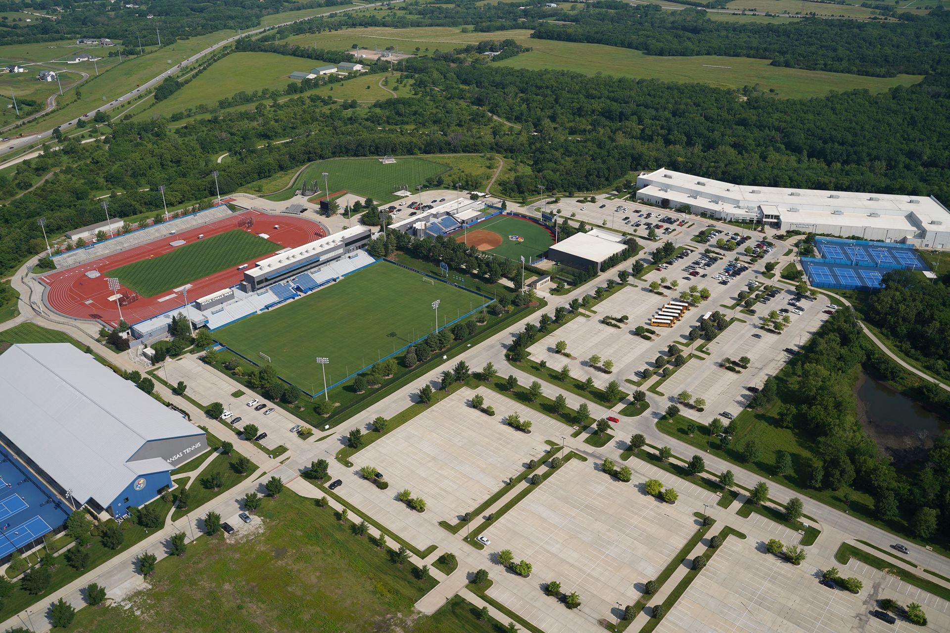 An aerial view of a stadium with a baseball field and a tennis court
