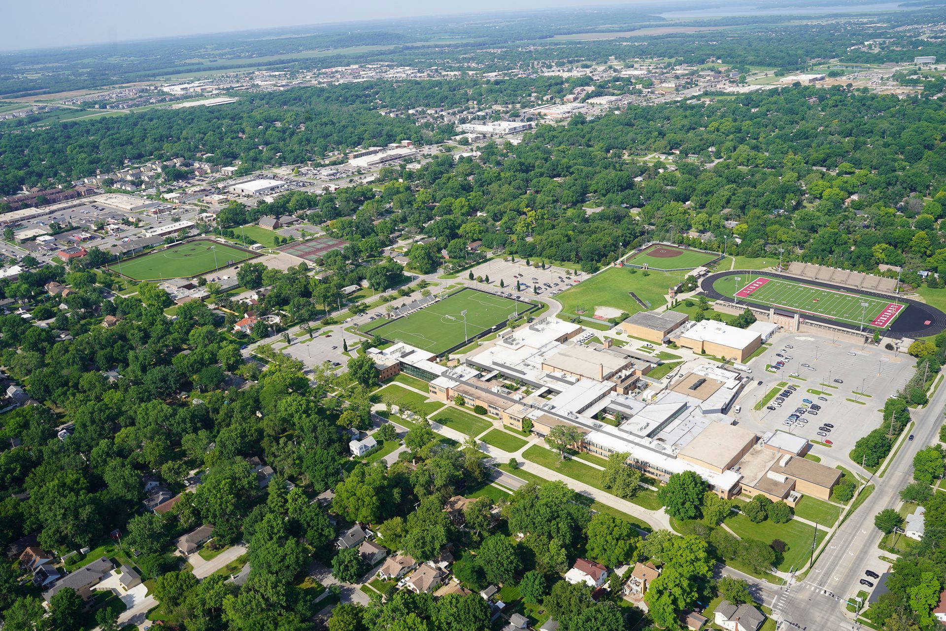 An aerial view of a school surrounded by trees and houses