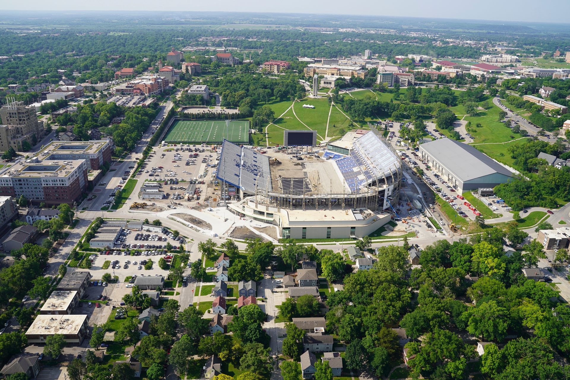 An aerial view of a large stadium in the middle of a city surrounded by trees.