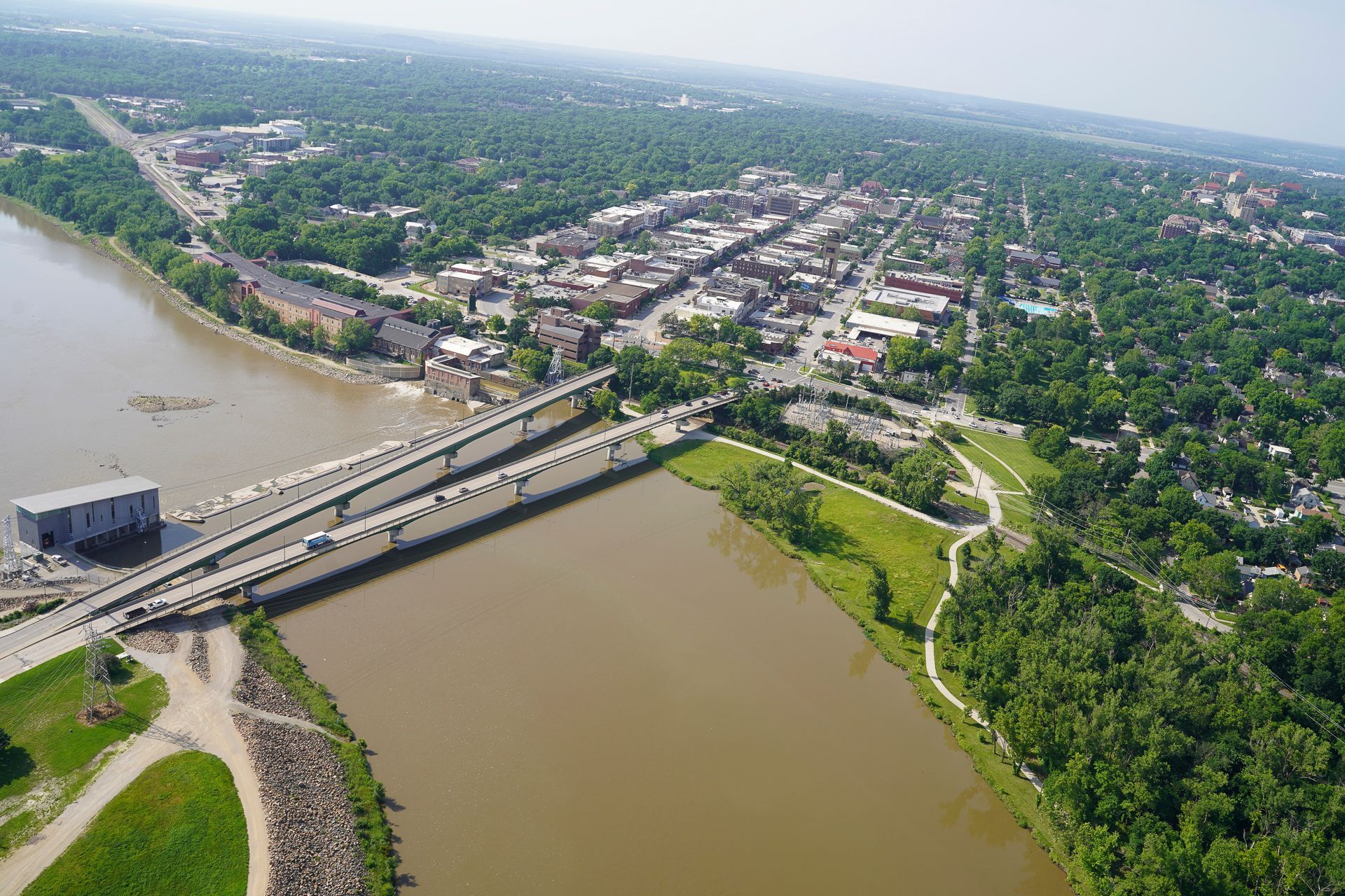 An aerial view of a bridge over a river with a city in the background.