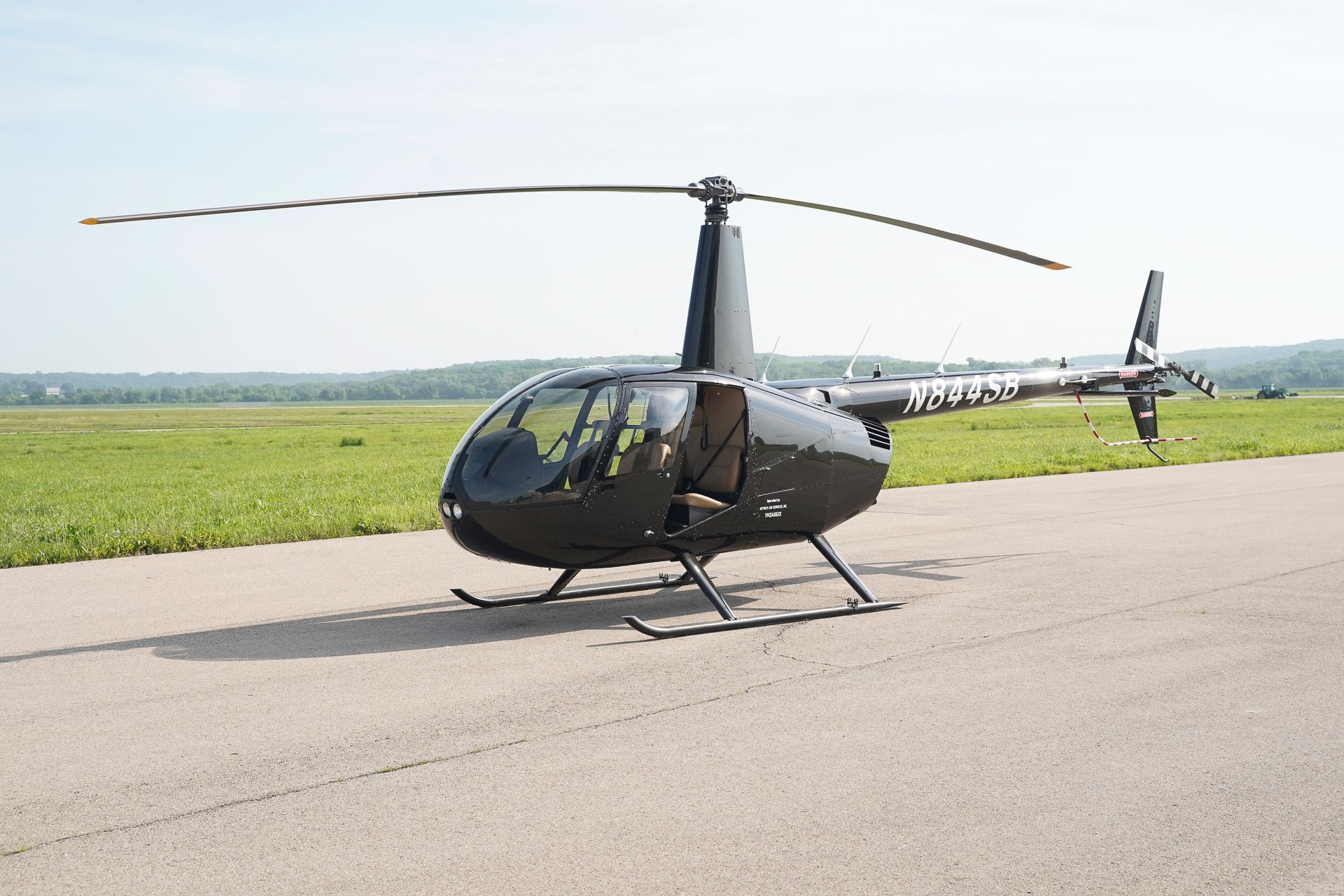 A small black helicopter is parked on a runway.