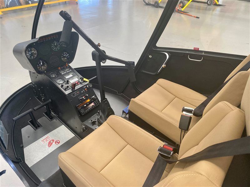 The inside of a helicopter with tan seats and a black cockpit