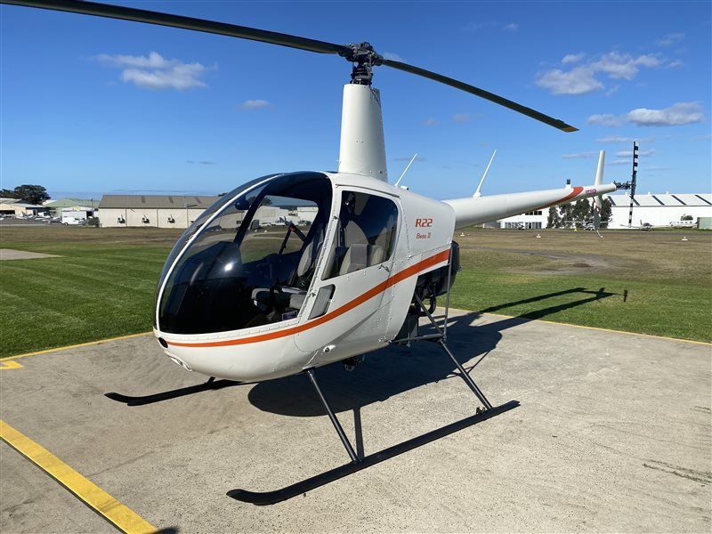 A small helicopter is parked on a concrete runway