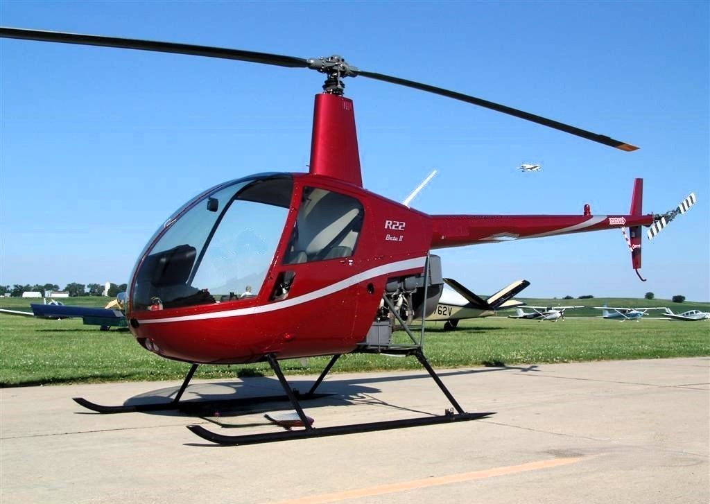 A small red helicopter is parked on a runway