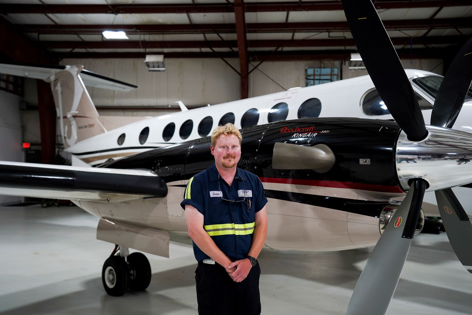 A man is standing in front of an airplane in a hangar.