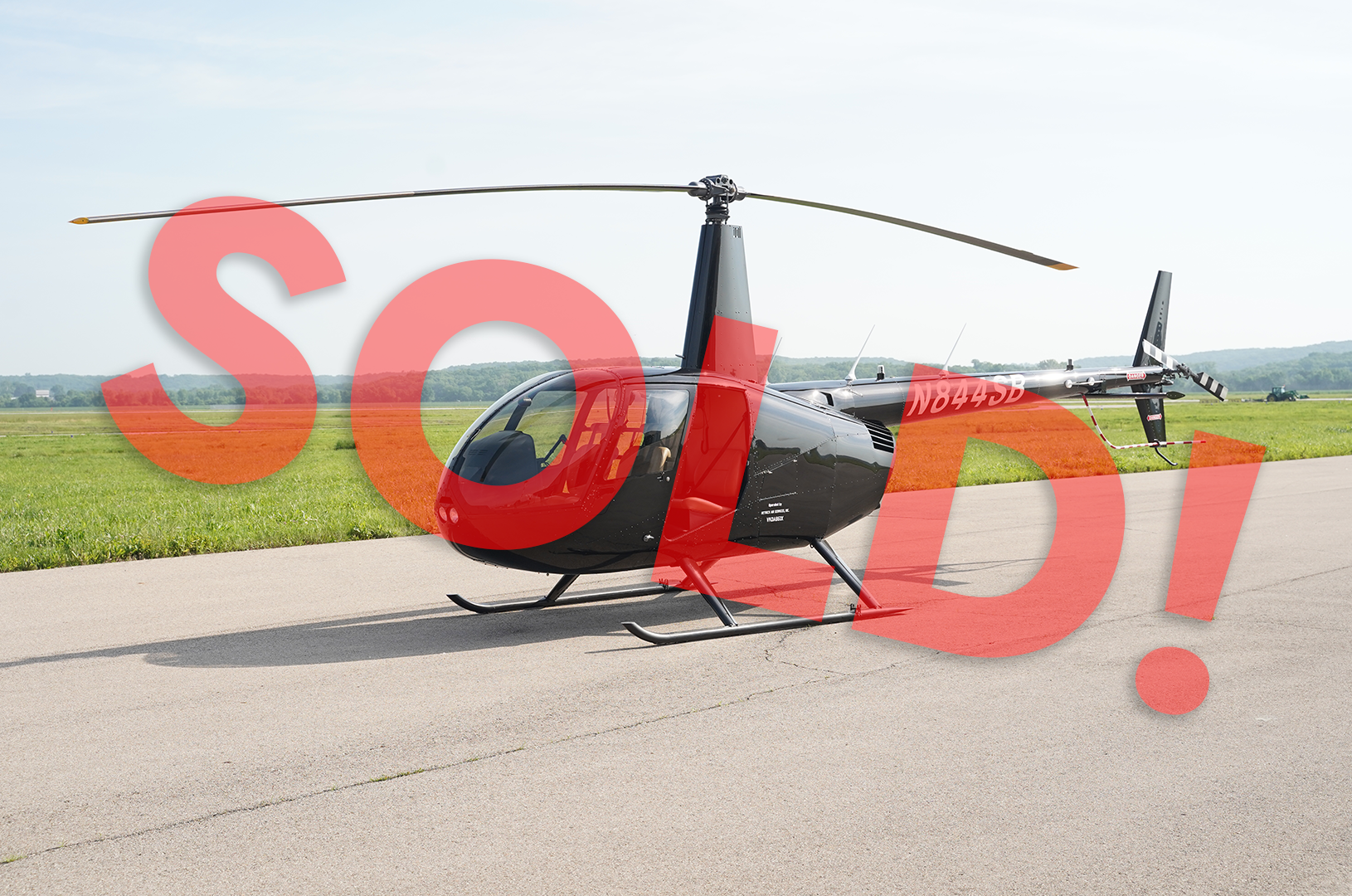 A small black helicopter is parked on a runway. Sold!