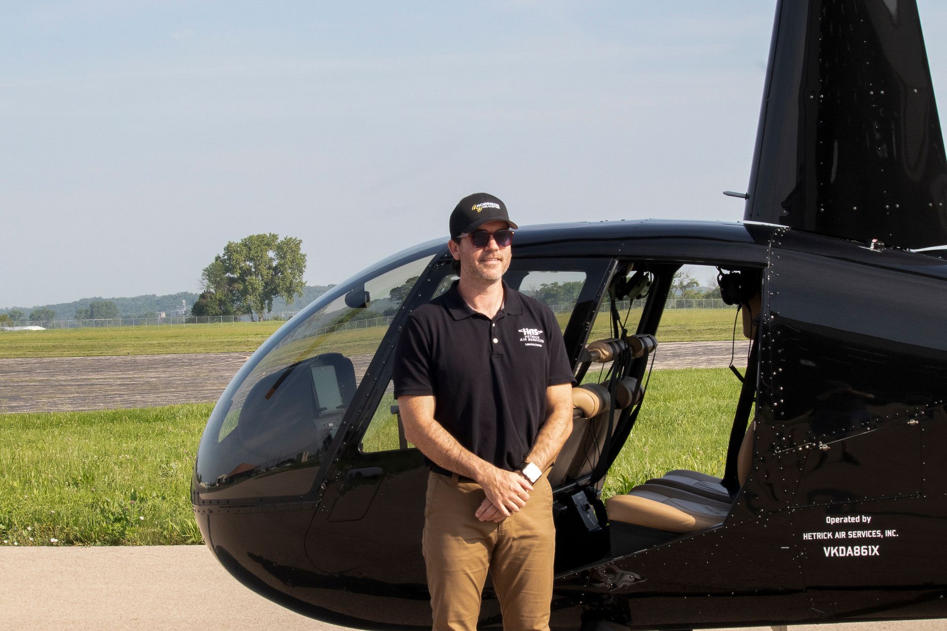 A man is standing in front of a black helicopter.