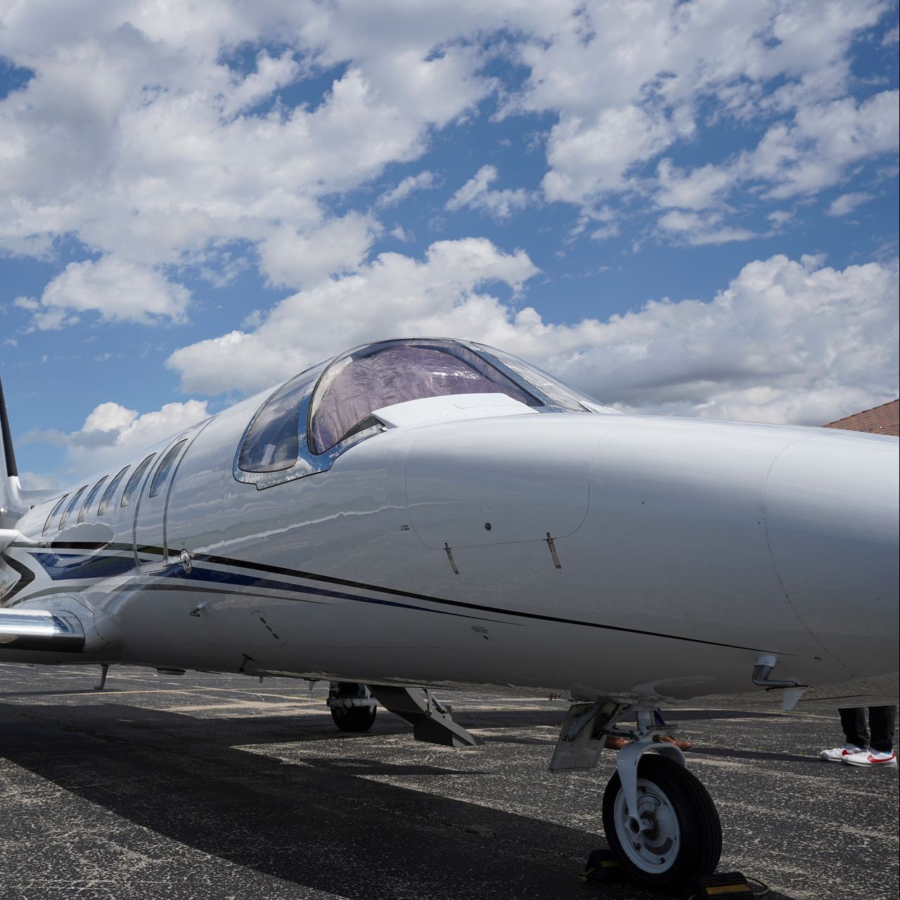 A small plane is parked on a runway with a blue sky in the background.