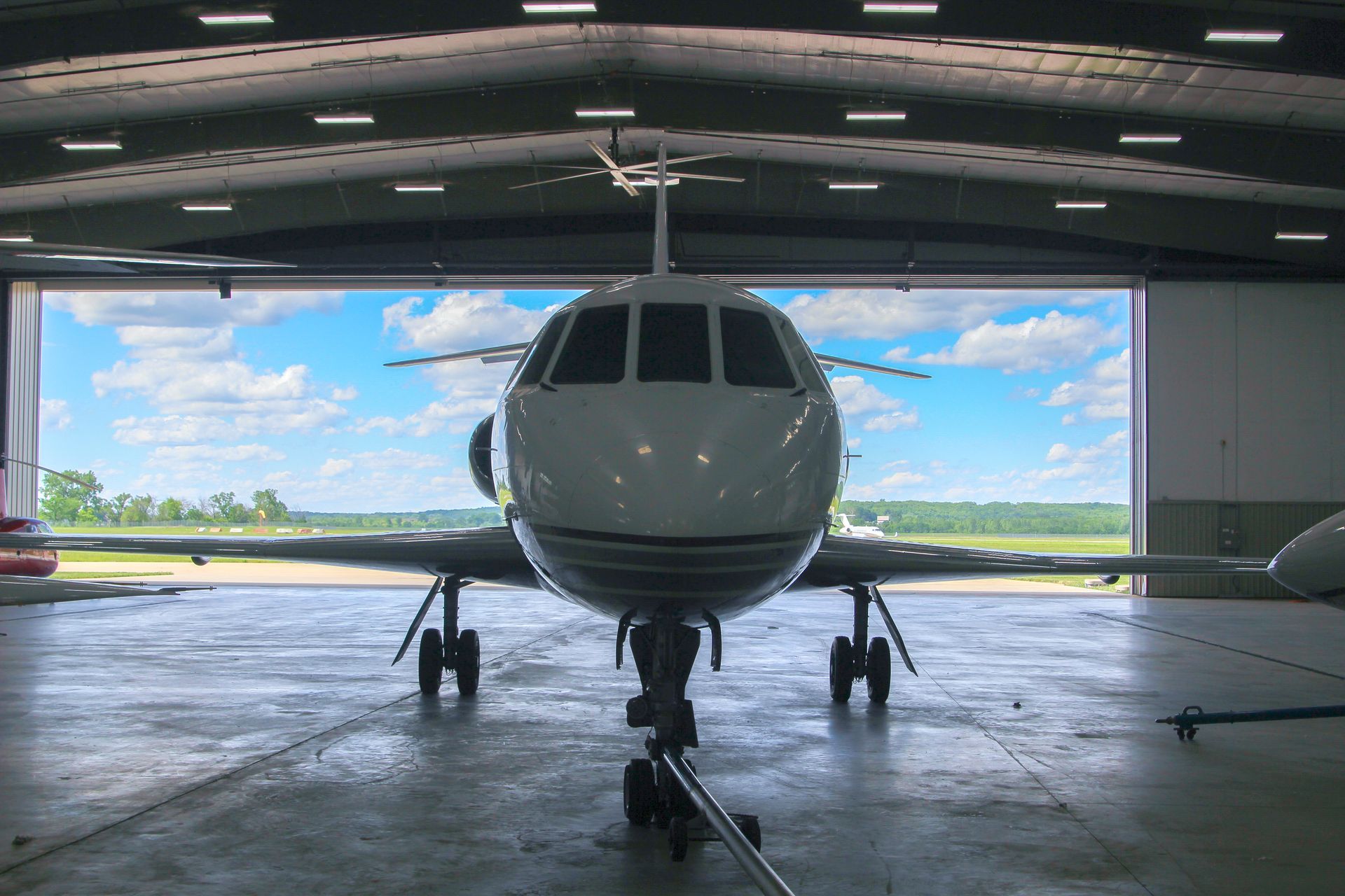 A plane is parked in a hangar with the door open
