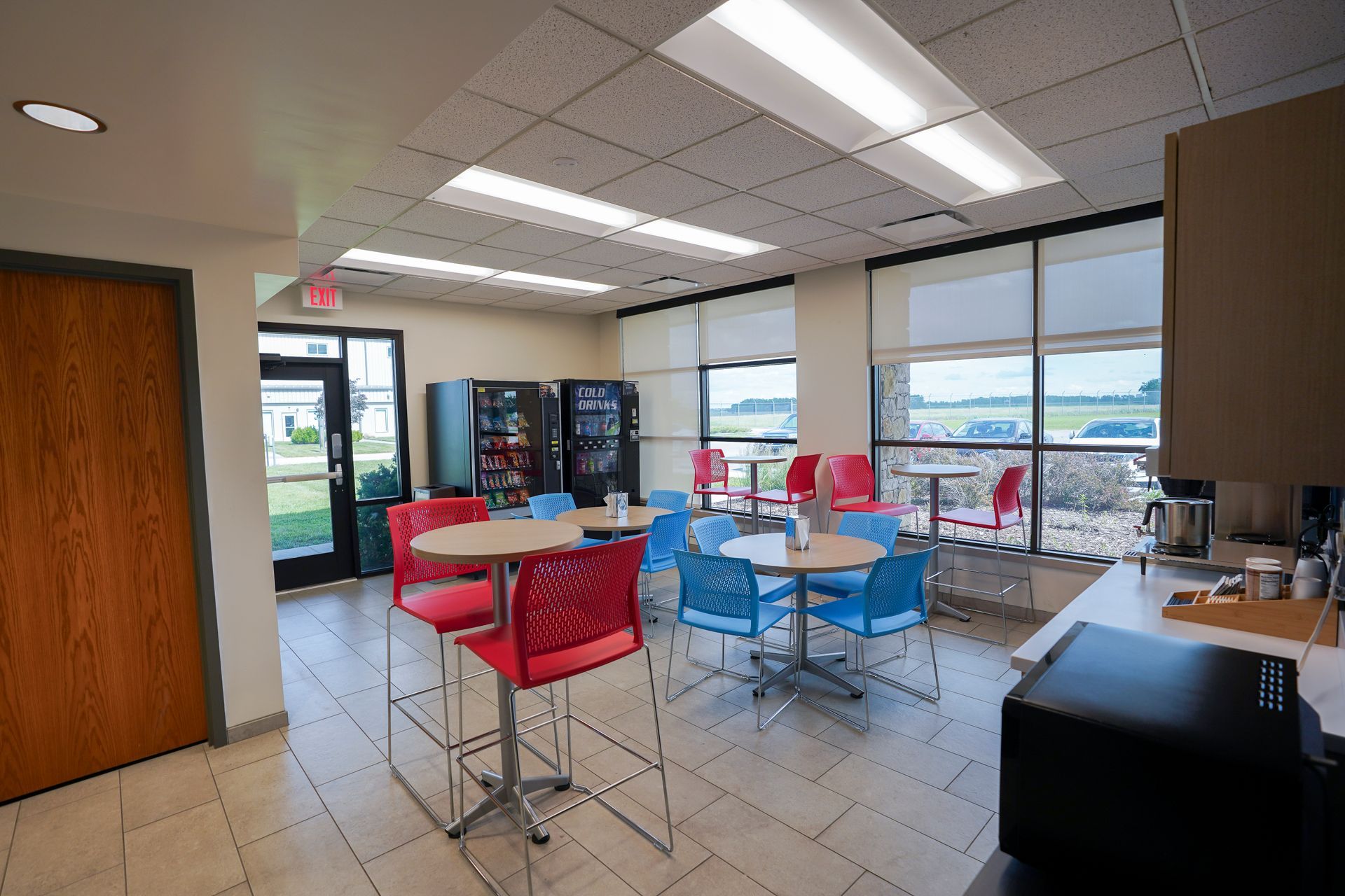 A room with tables and chairs in it and a vending machine.