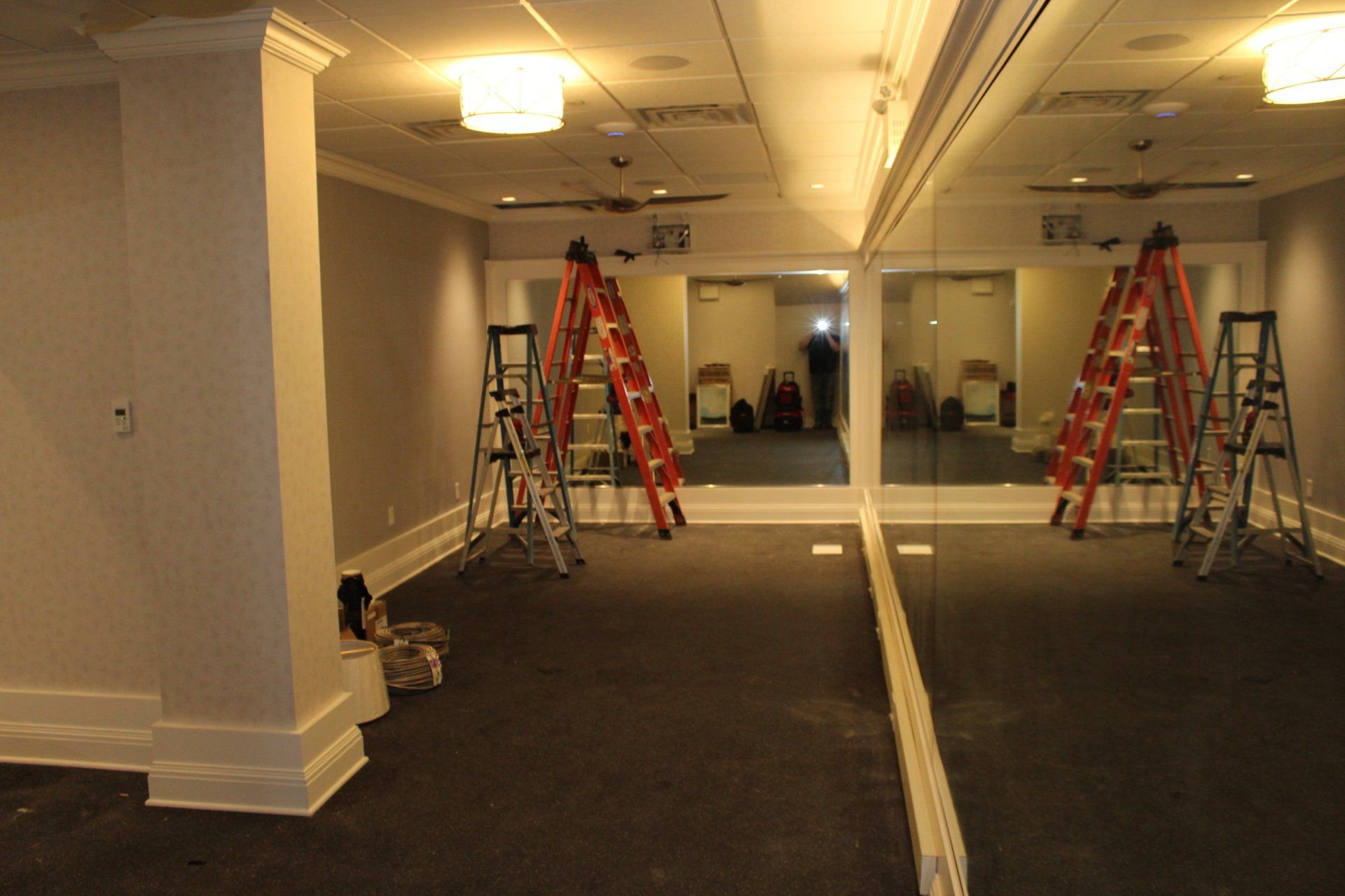 Fitness room under renovation with ladders, mirrors, and carpeting at The Reeds at Shelter Haven.