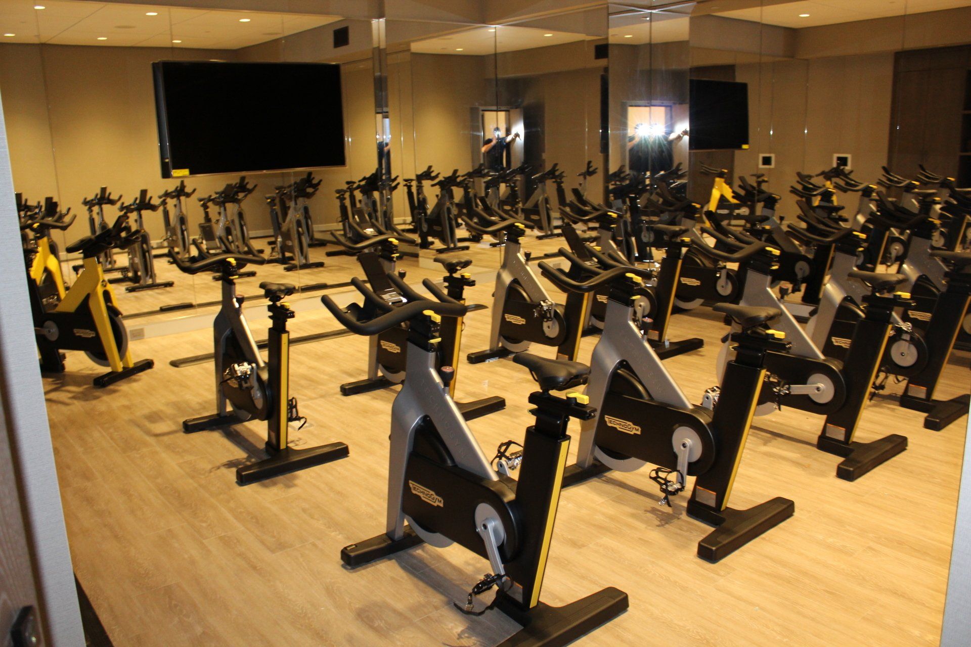 Fitness room filled with black and yellow spin bikes for cycling classes.