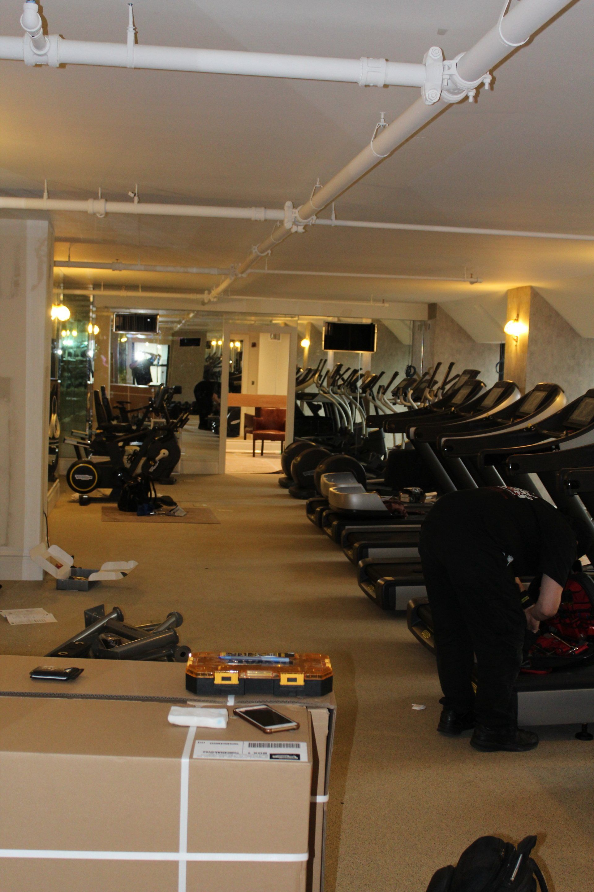 Row of treadmills in Lotte New York Palace fitness center with mirrored walls and warm lighting.