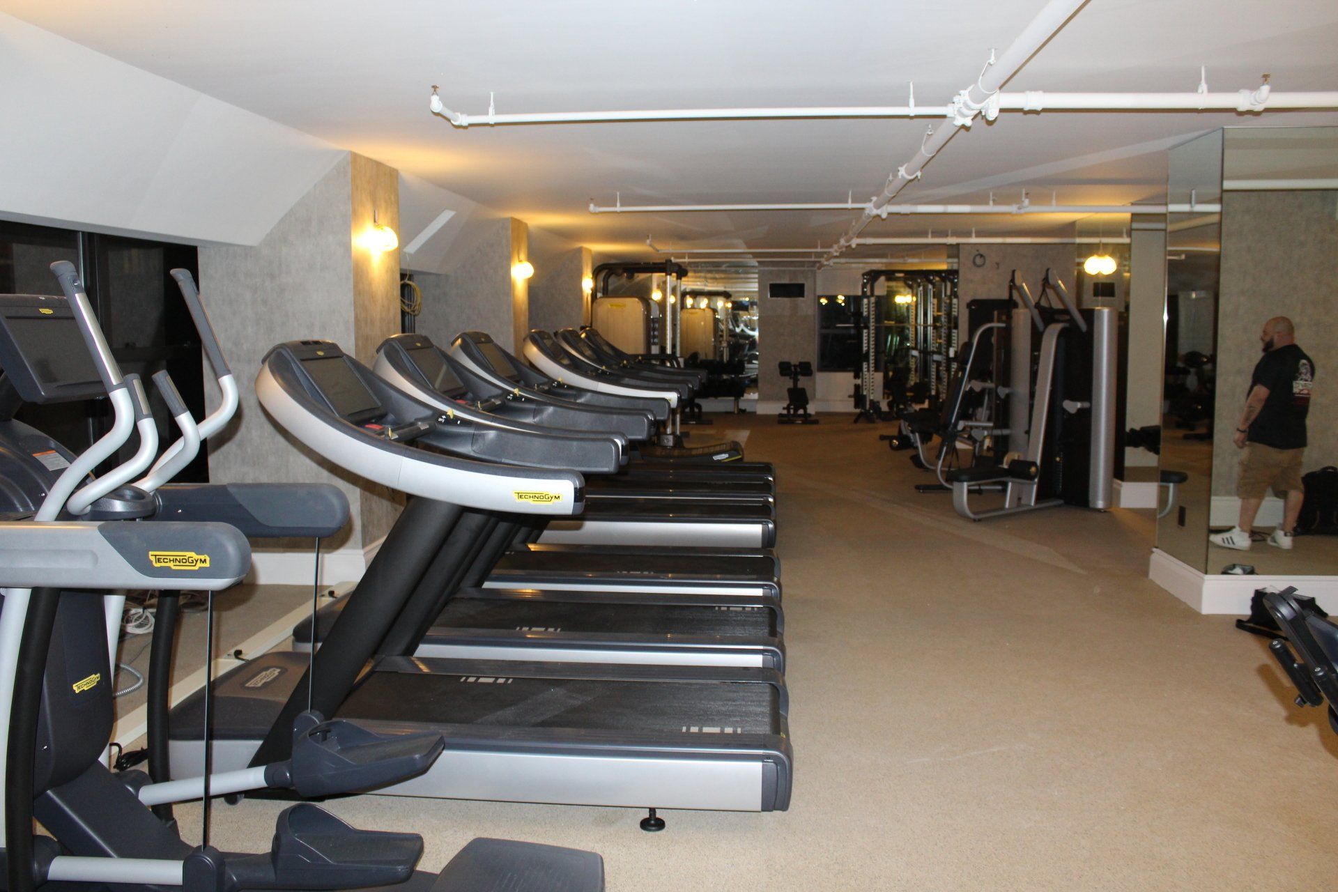 Treadmills lined up with mirrored walls in Lotte New York Palace gym space.