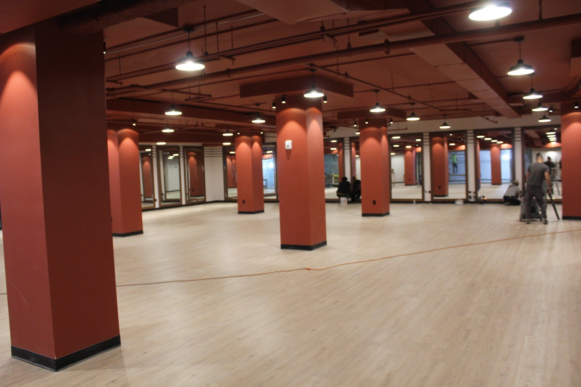 Open gym area with red columns and wooden floors at Twenty Exchange Place fitness center.