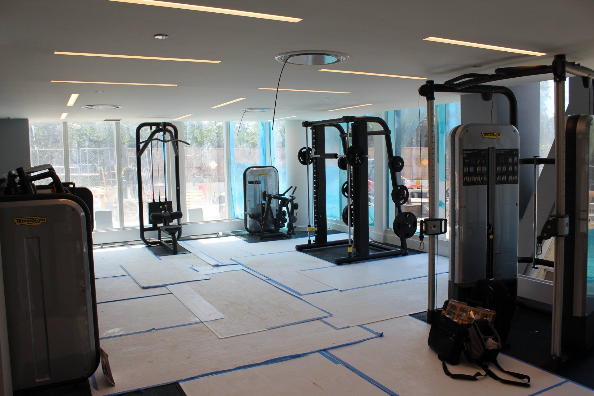 New gym setup at Quay Tower with fitness machines installed on protective floor covering.