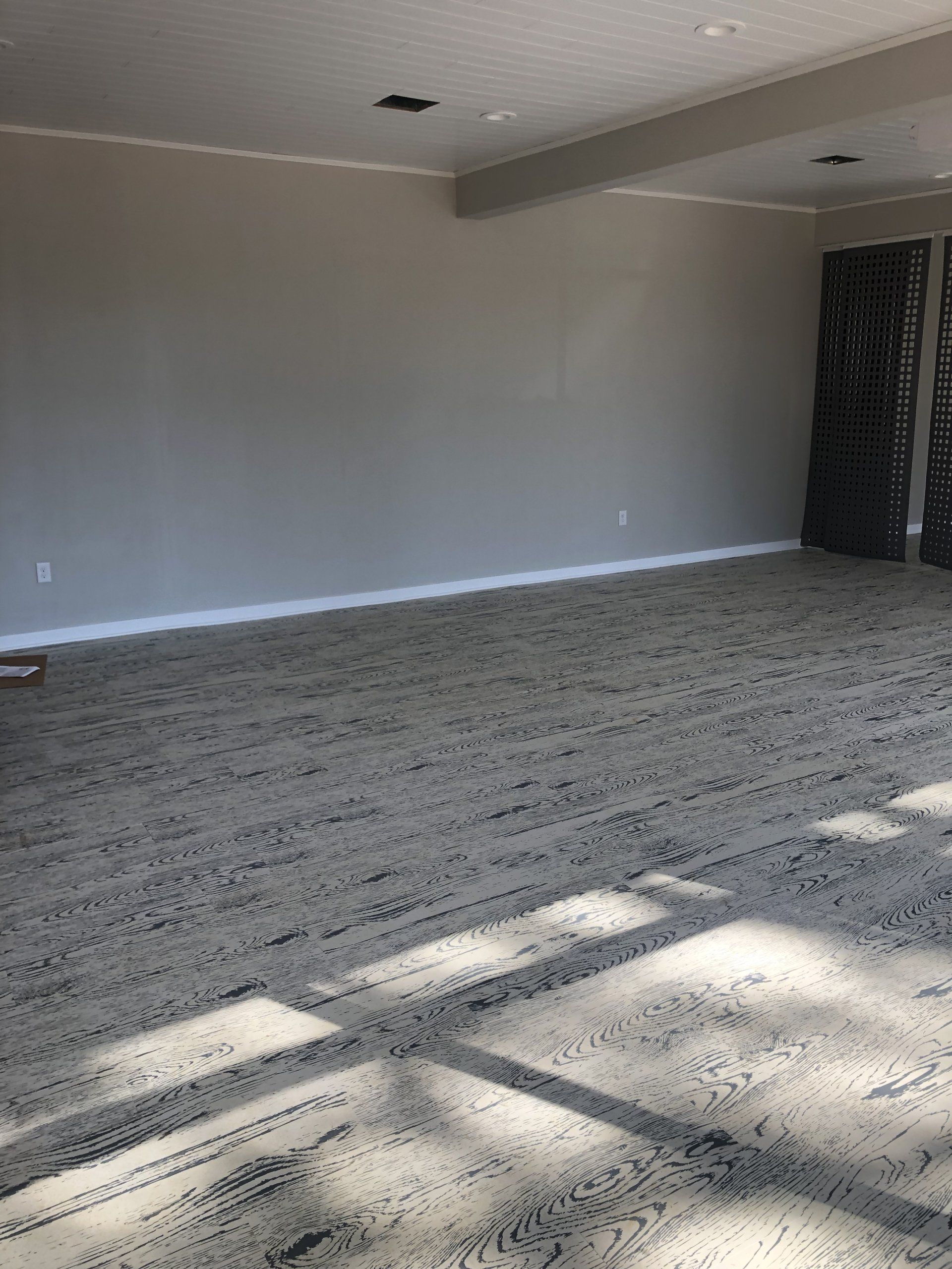 Spacious empty room with natural light and wood flooring at Daily Fitness.