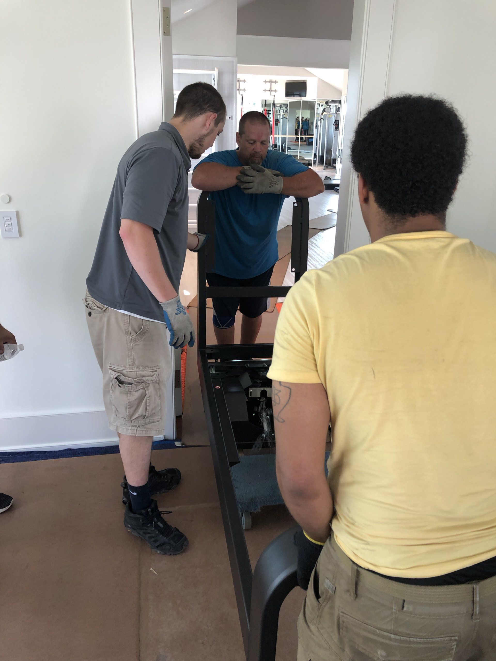 Team positioning exercise machine during Bridgehampton residential gym installation.