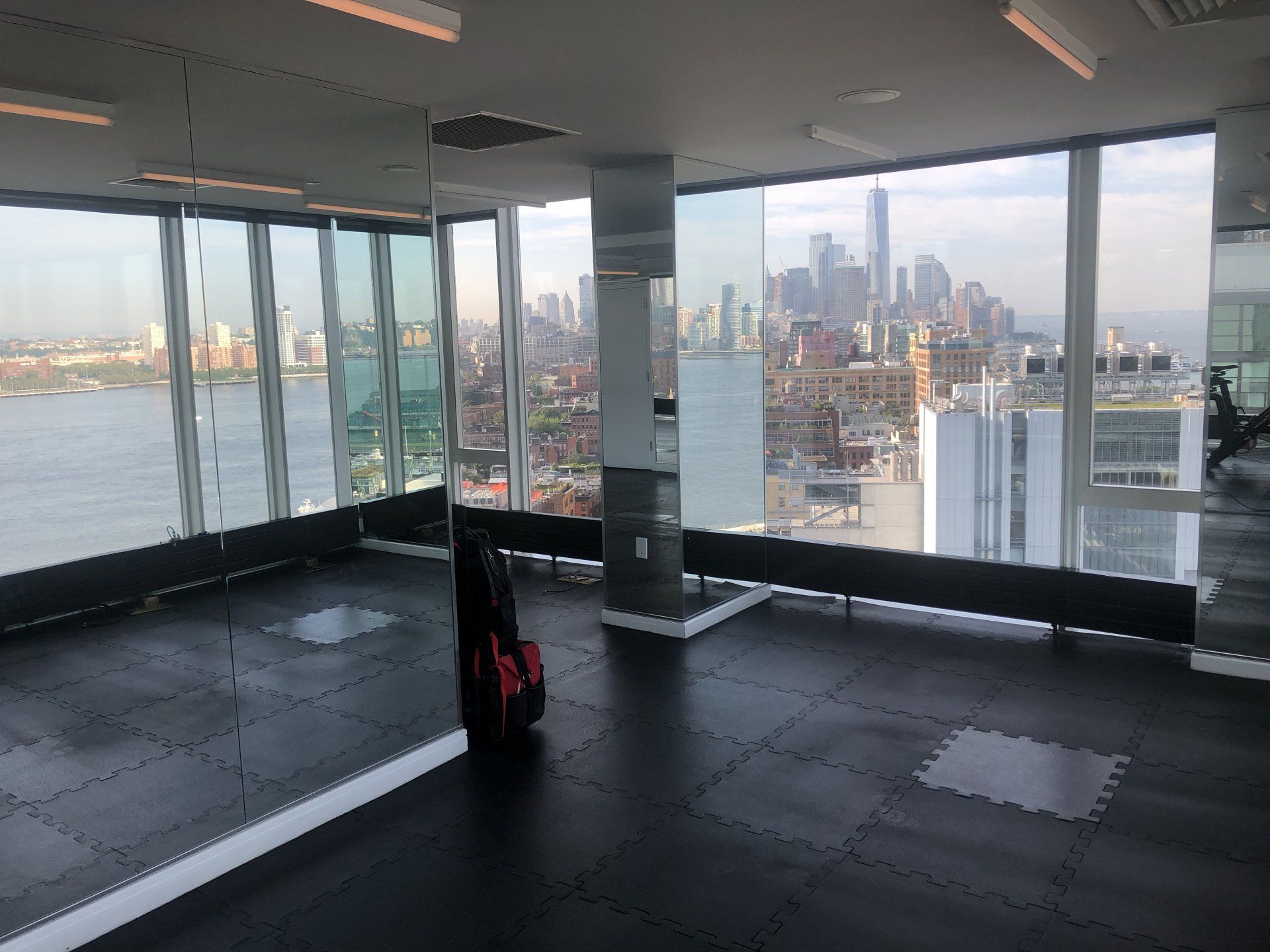 Spacious workout area at The Standard with panoramic windows overlooking New York City skyline.