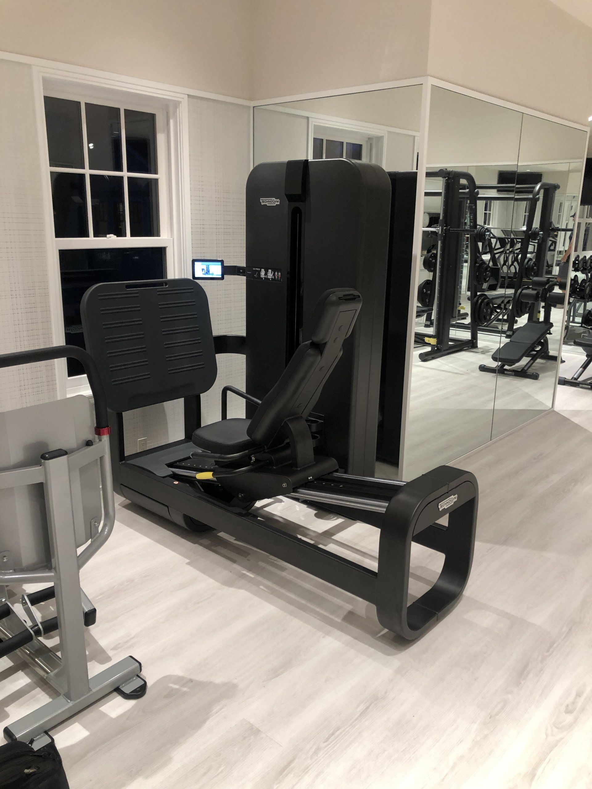 Leg press machine setup in sleek home gym at Bridgehampton residential build