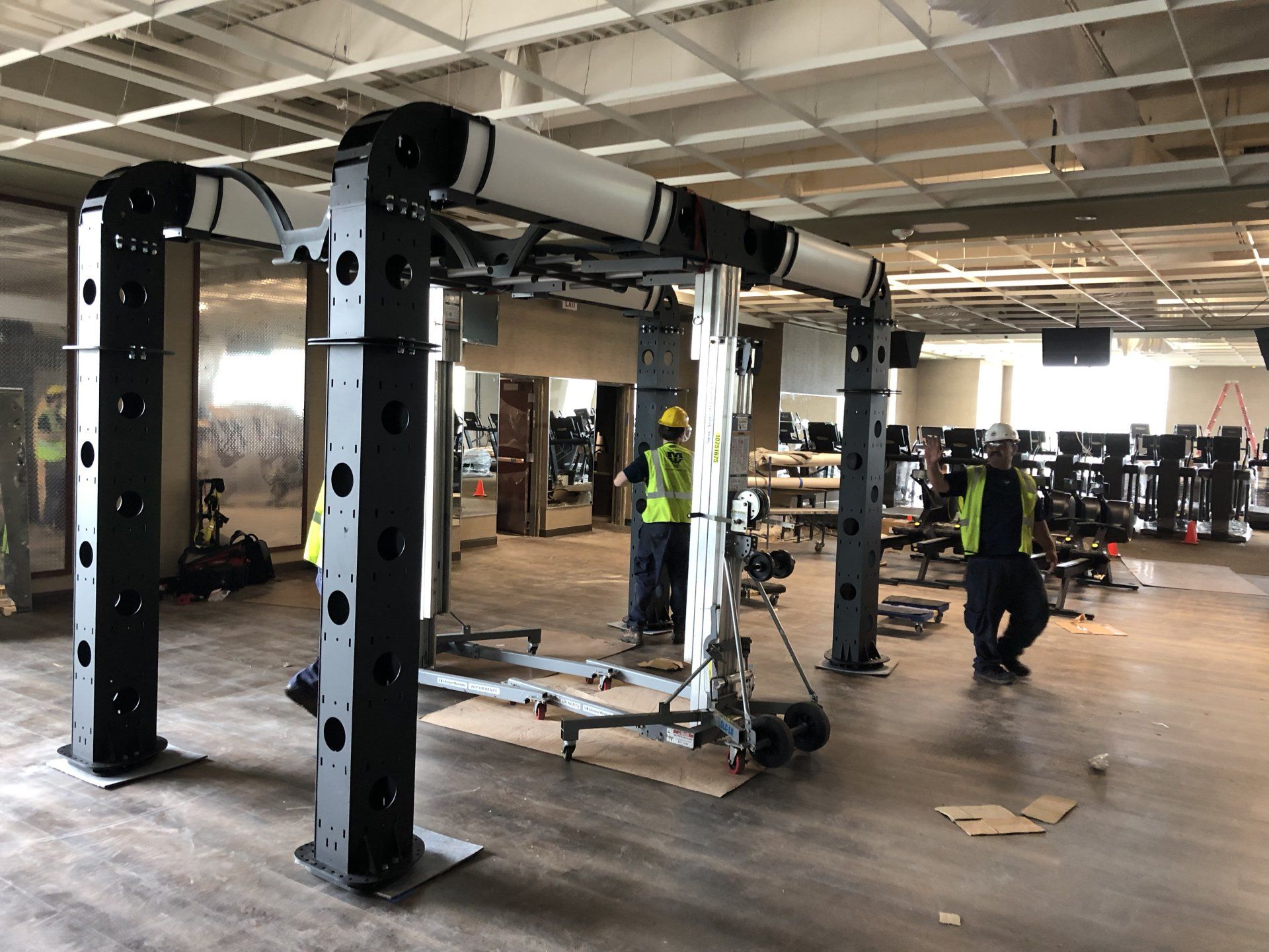 Workers setting up large strength training equipment at Lifetime Athletics gym.