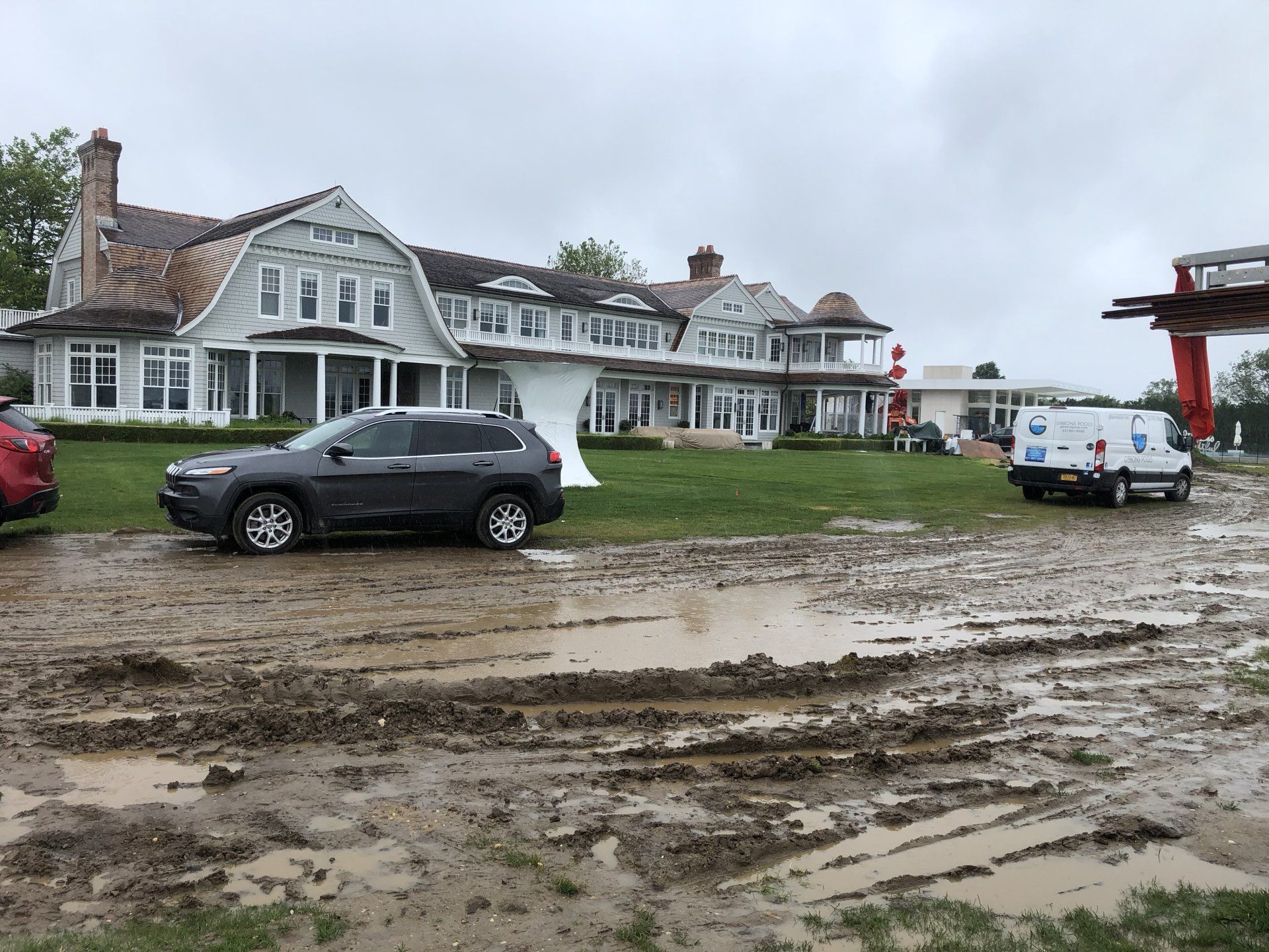 Luxury home exterior under construction with muddy driveway in Bridgehampton