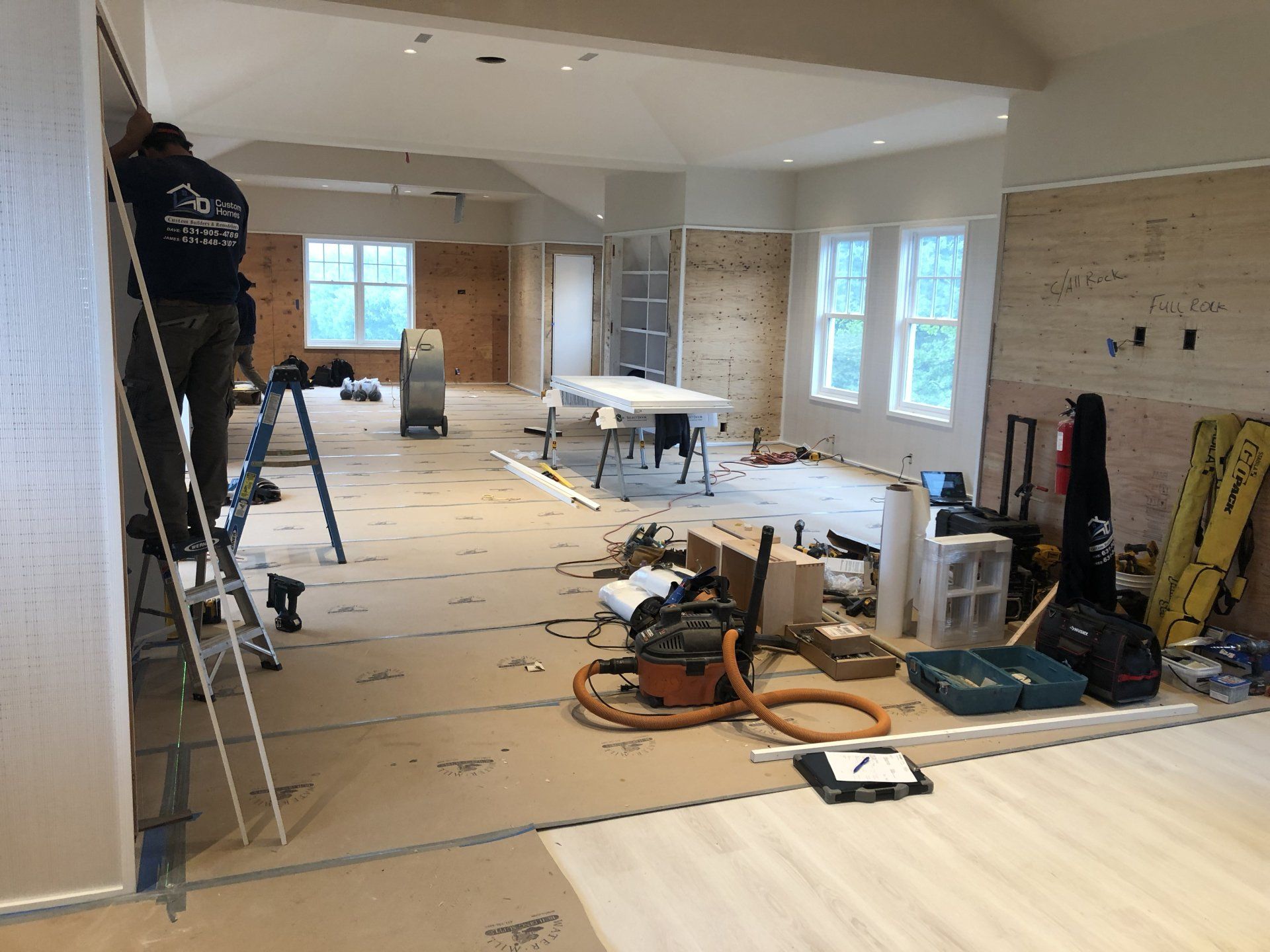 Residential interior under renovation with tools and ladders on site.