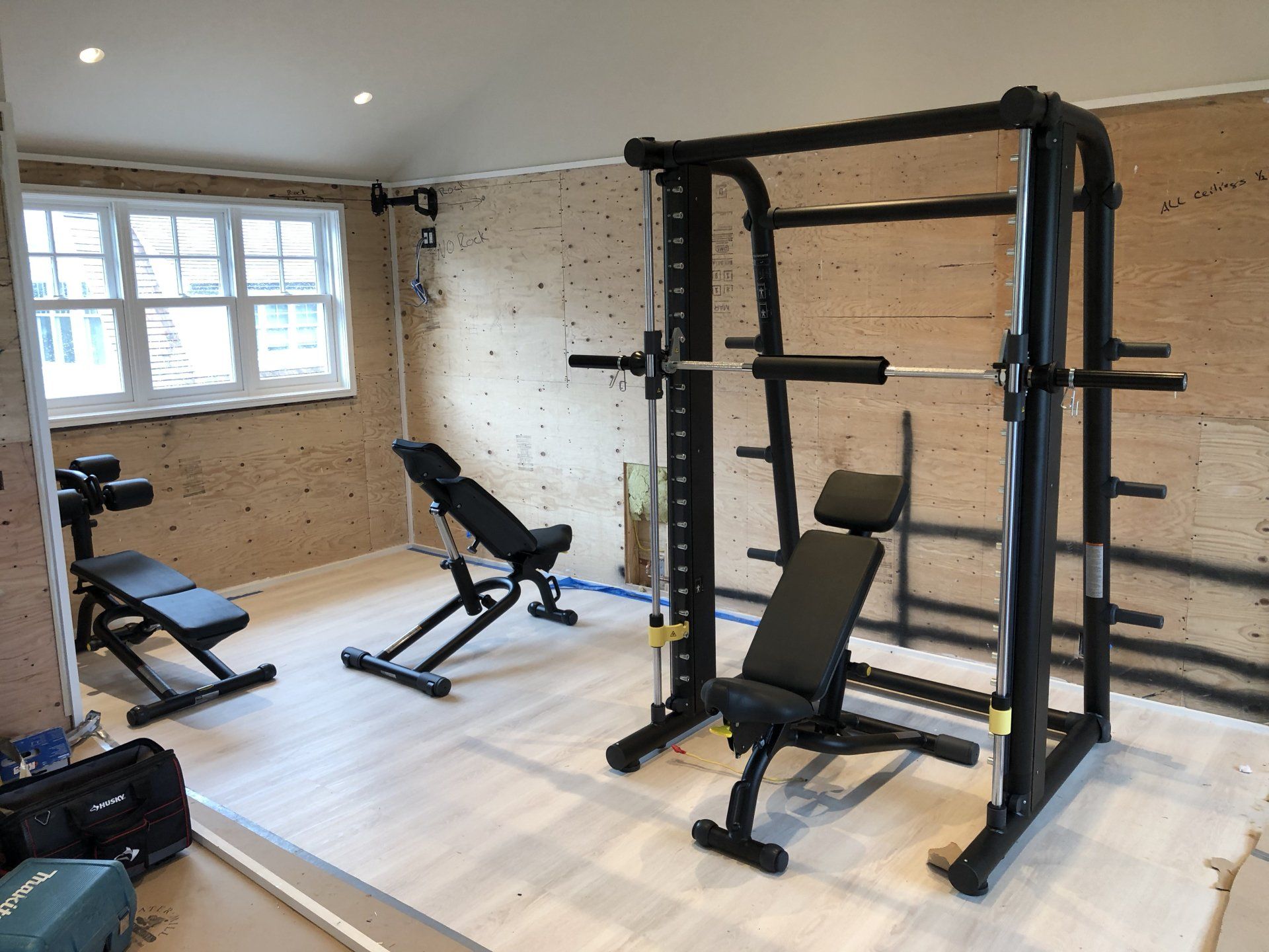 Home gym in progress with squat rack and weight bench installed in Bridgehampton residence.