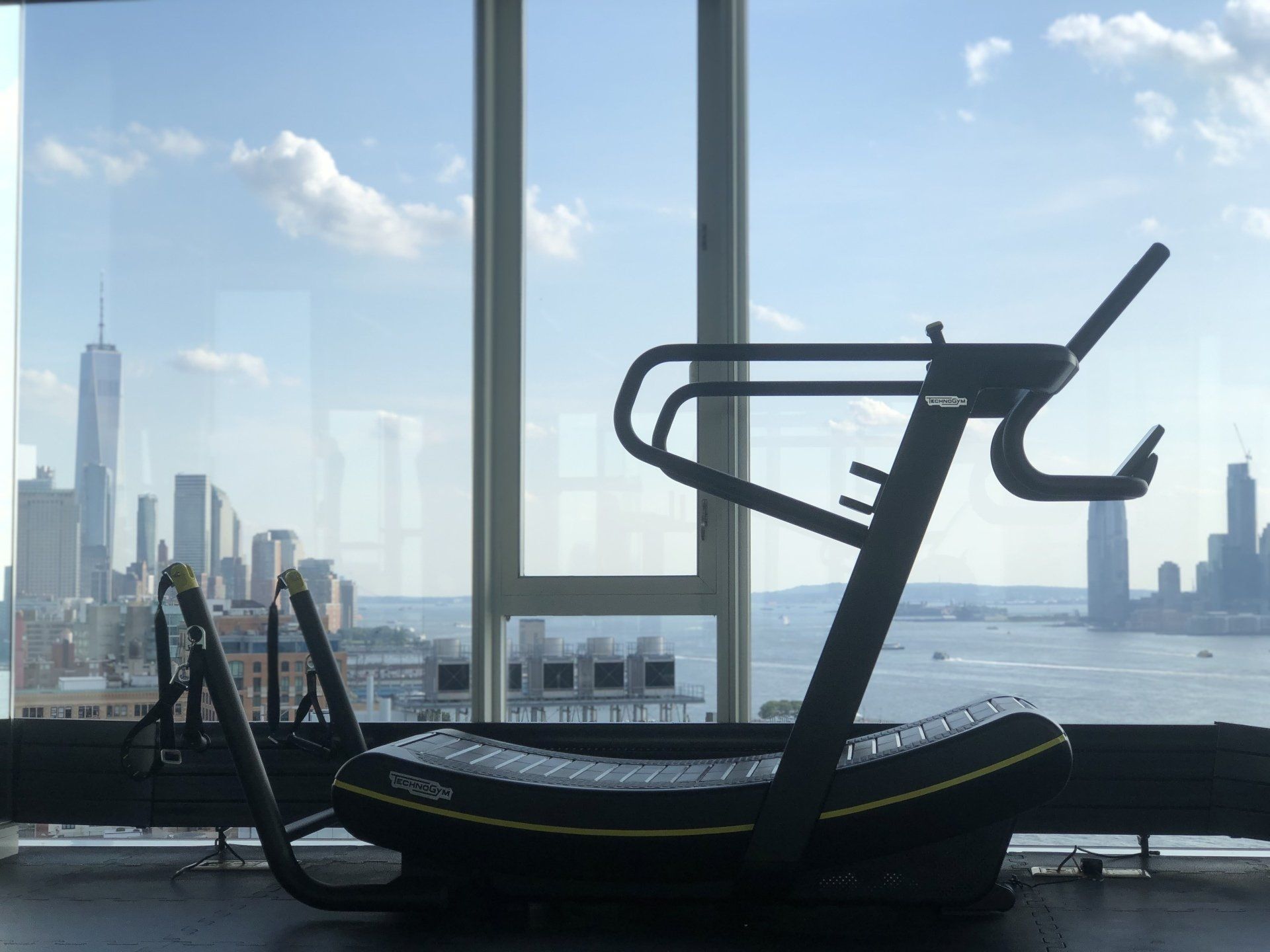 Treadmill facing floor-to-ceiling windows with New York City skyline view at The Standard gym.